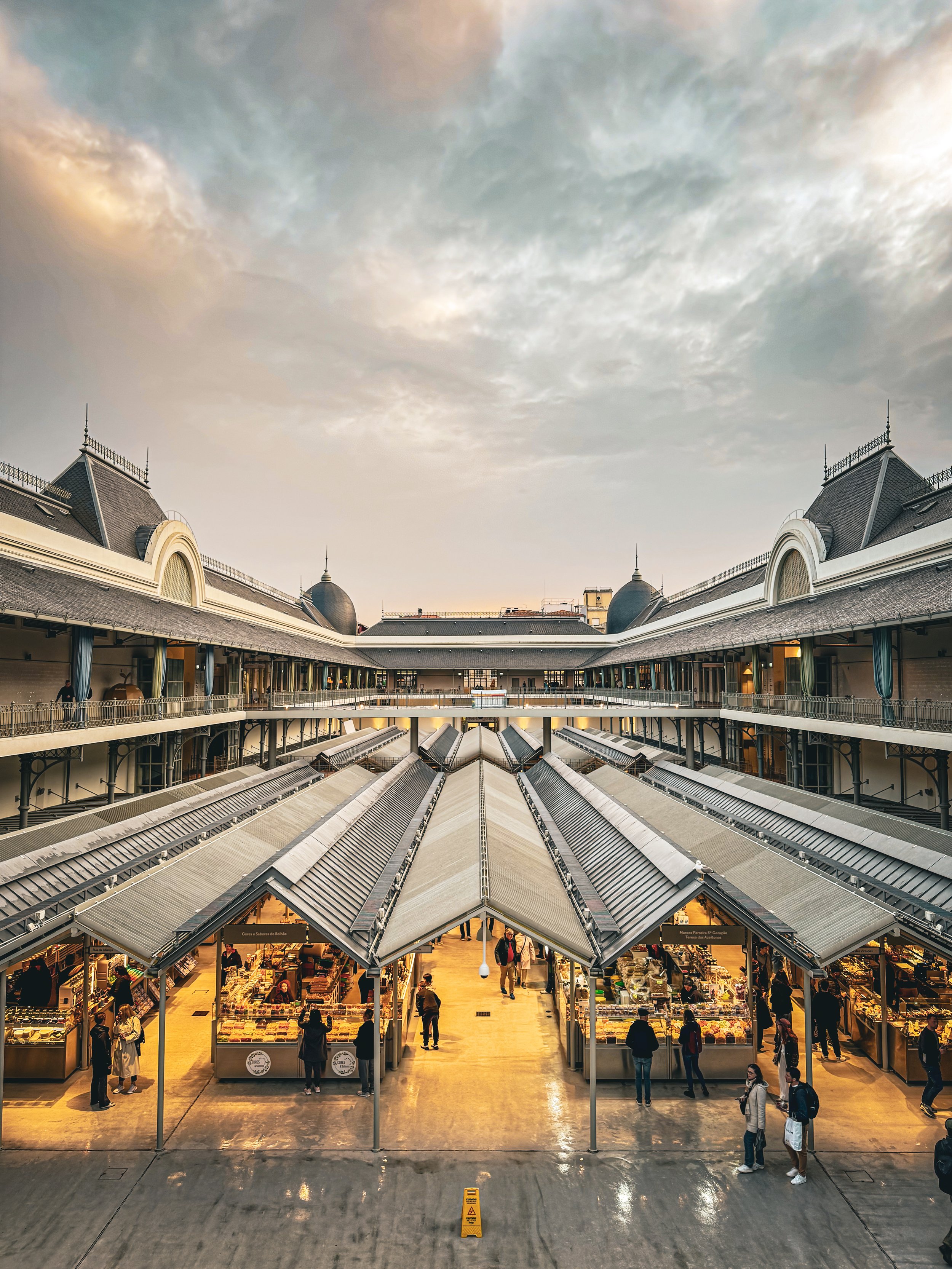 A film and photo location in Portugal from walnut films, View of Mercado Central, a two-story market with shops selling food and goods. Shoppers are seen walking and browsing inside,. The market features a mix of traditional and modern architecture,