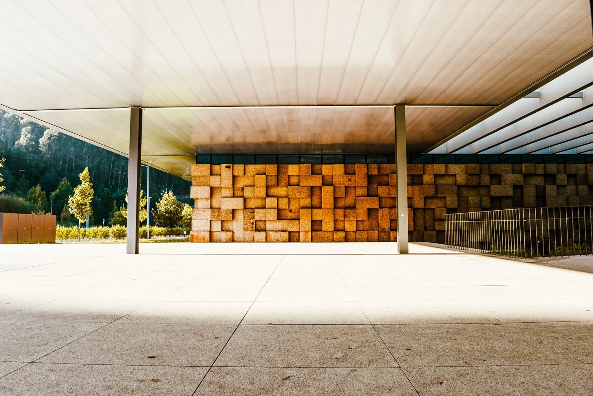 A film and photo location in Portugal from walnut films, Modern building with a wooden ceiling, brick wall, trees, and clear sky.