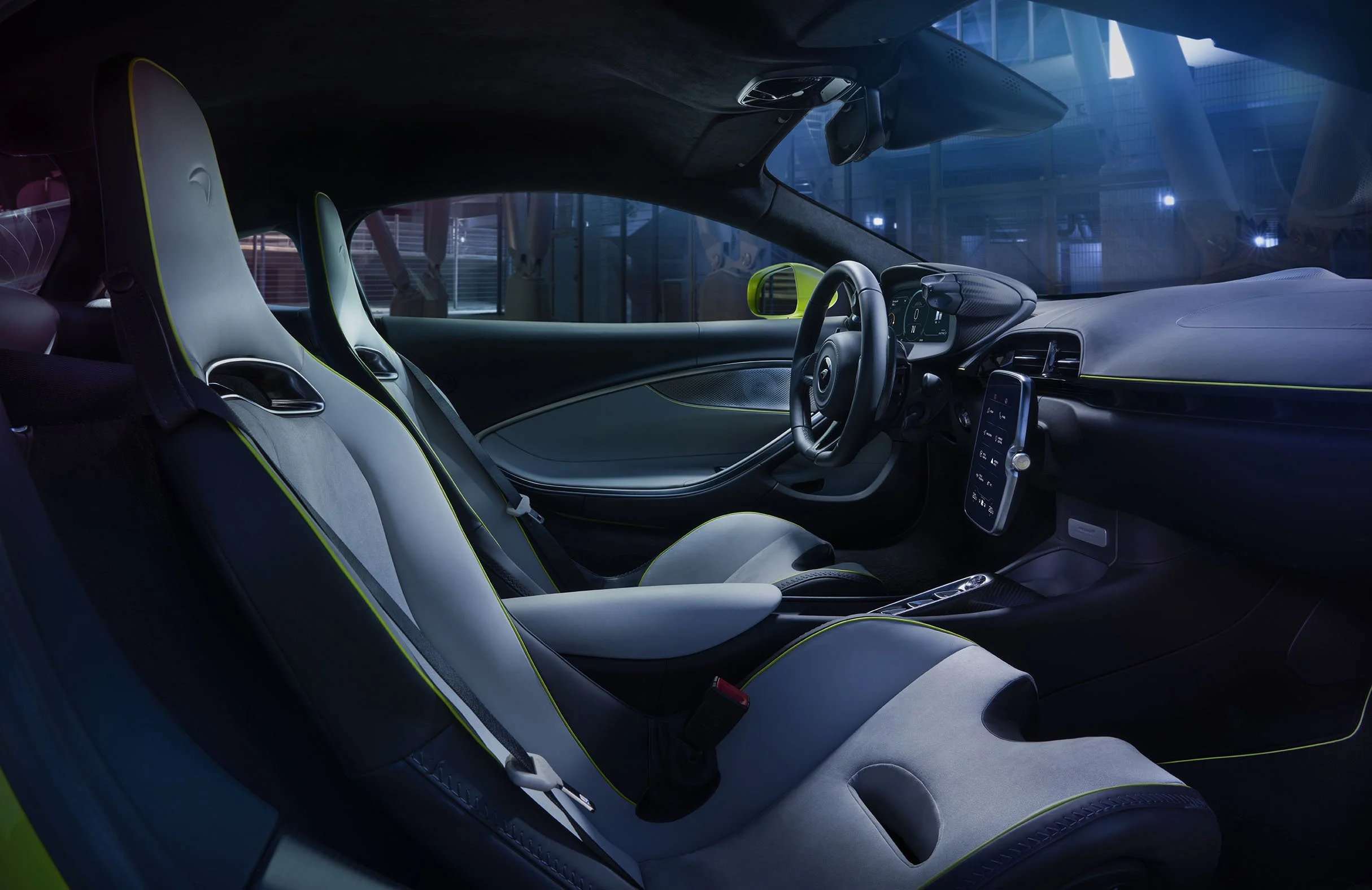 Interior of a modern sports car featuring two white racing seats, a digital dashboard, and a steering wheel, with city buildings visible through the windows.