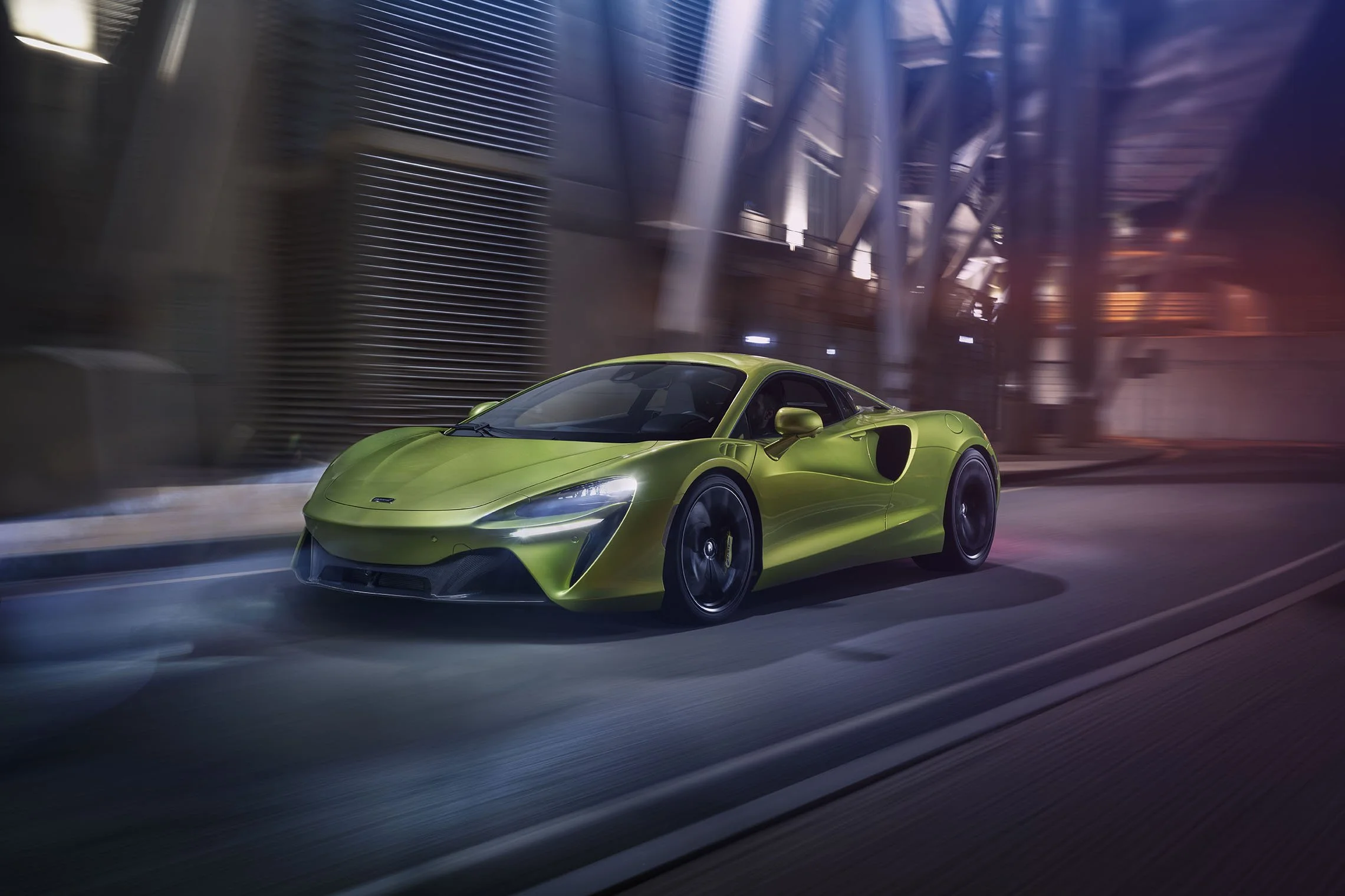 A bright green sports car driving on a city street with tall buildings and neon lights in the background.