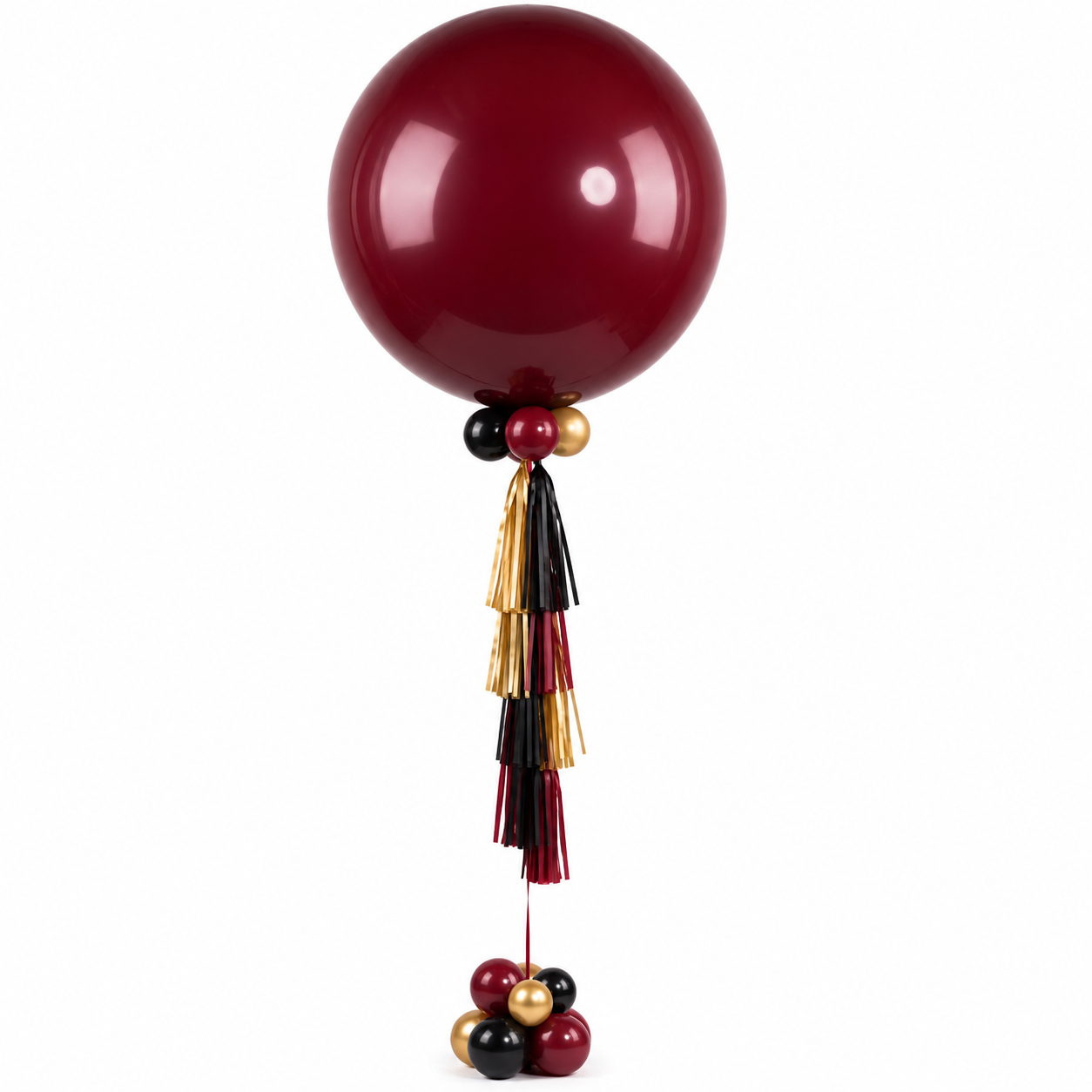Balloons arranged in a decorative display with a large maroon balloon at the top, smaller black, gold, and maroon balloons below, and long tassels hanging down in black, maroon, and gold colors.