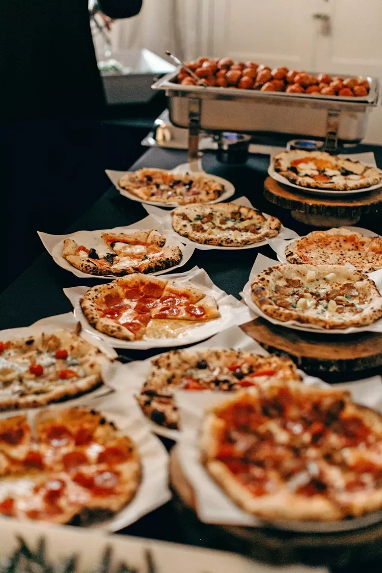 Variety of small pizzas on plates and a tray of meatballs on a table.