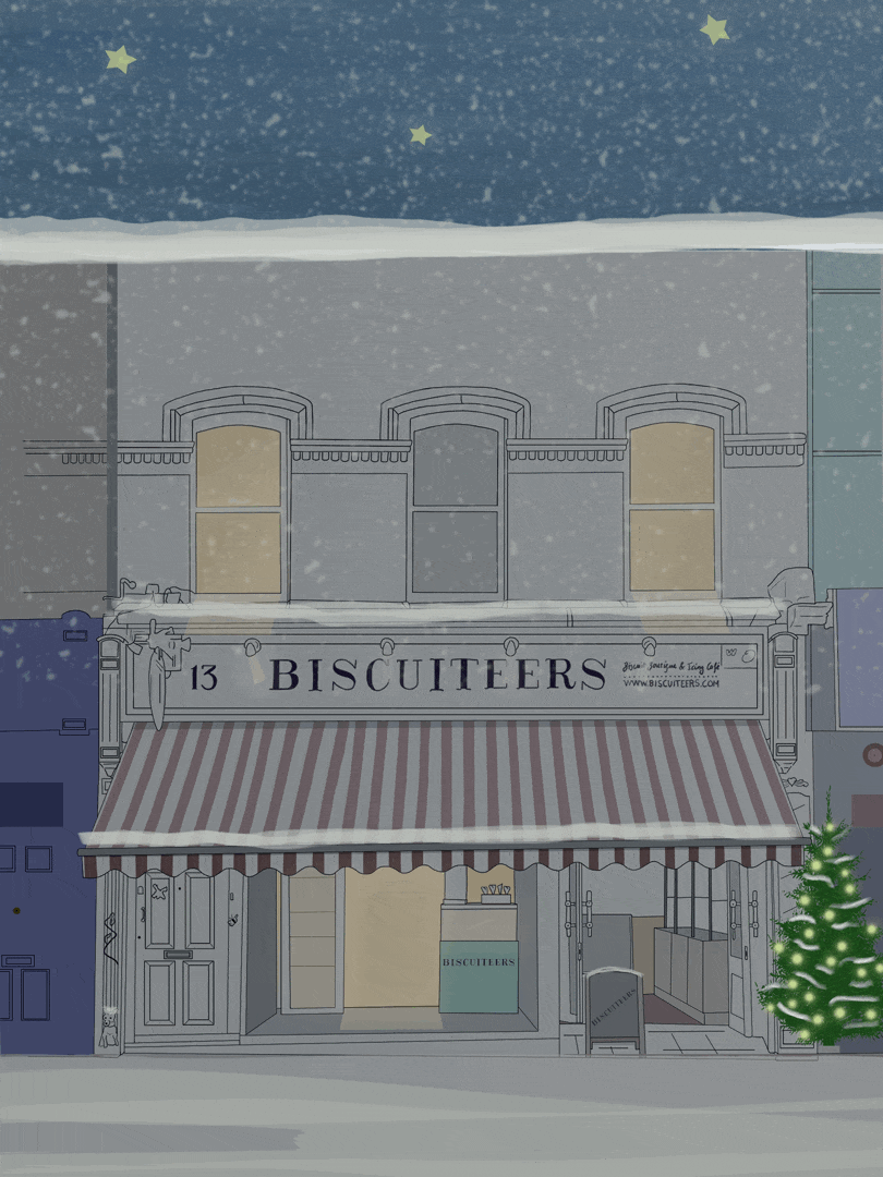 A snow-covered city street scene with a bakery named Biscuiteers, decorated for Christmas with an illuminated Christmas tree on the right side, snow falling, and snow on the rooftops and sidewalk.