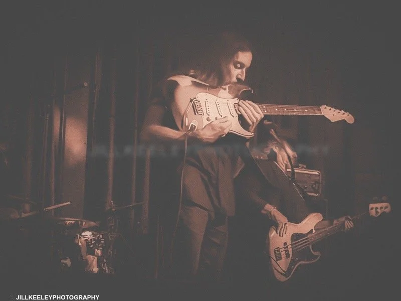 Musician on stage preforming with electric fender guitar.