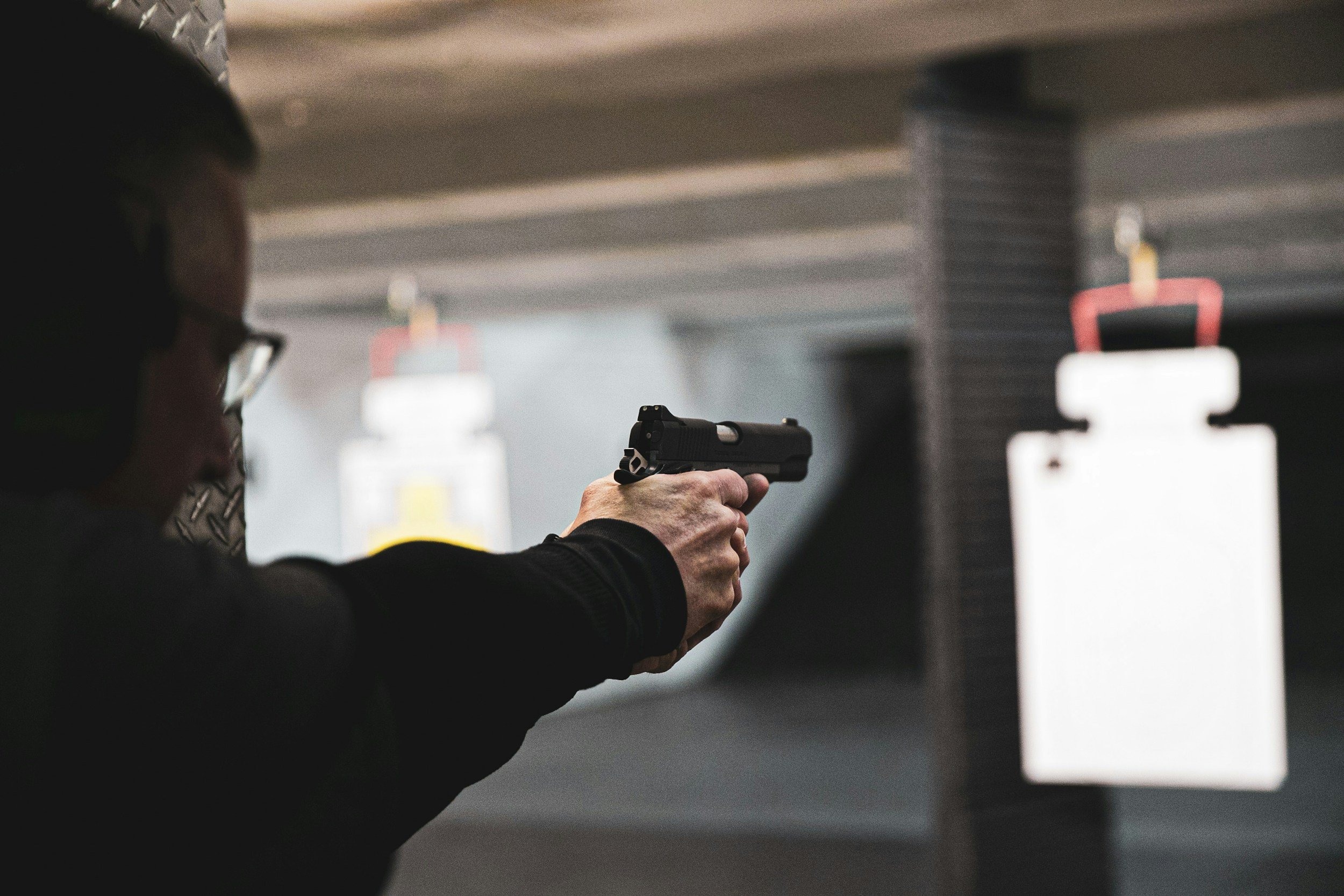 A person firing a pistol on a gun range