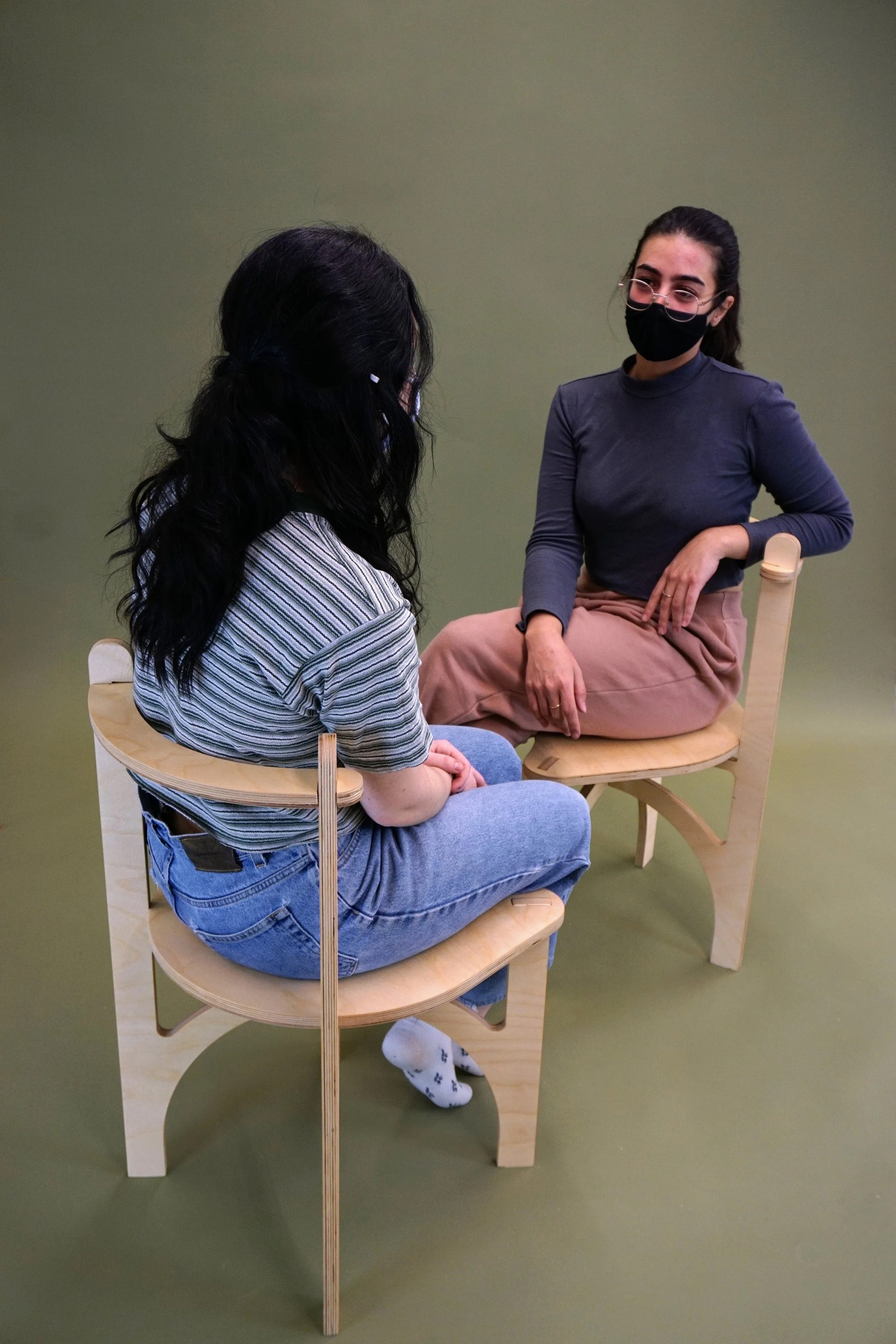 Two people sitting on the chairs facing each other and talking