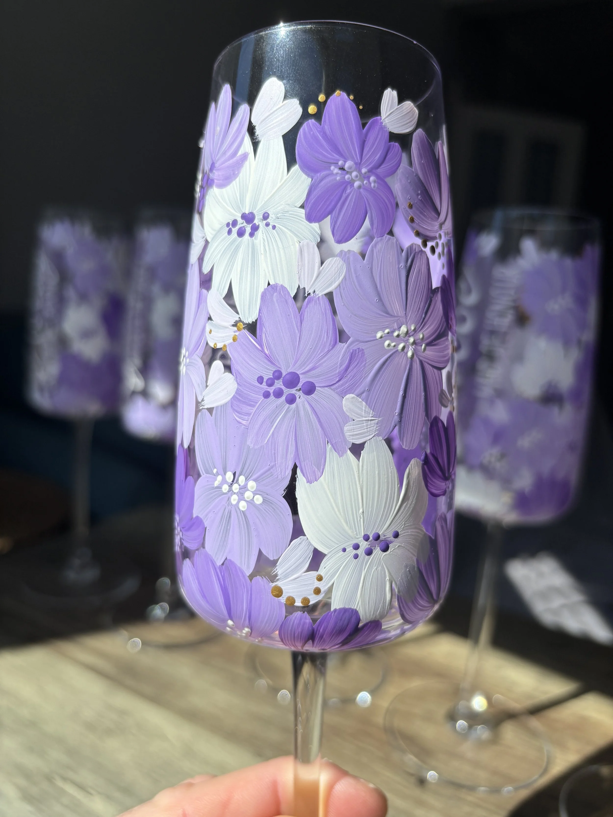 A clear glass filled with a decorative design of purple and white flowers and small gold accents.