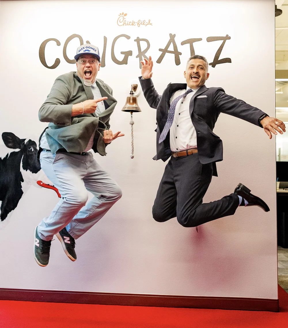 Alex Gomez and Kevin Williams jumping in front of a CONGRATZ backdrop