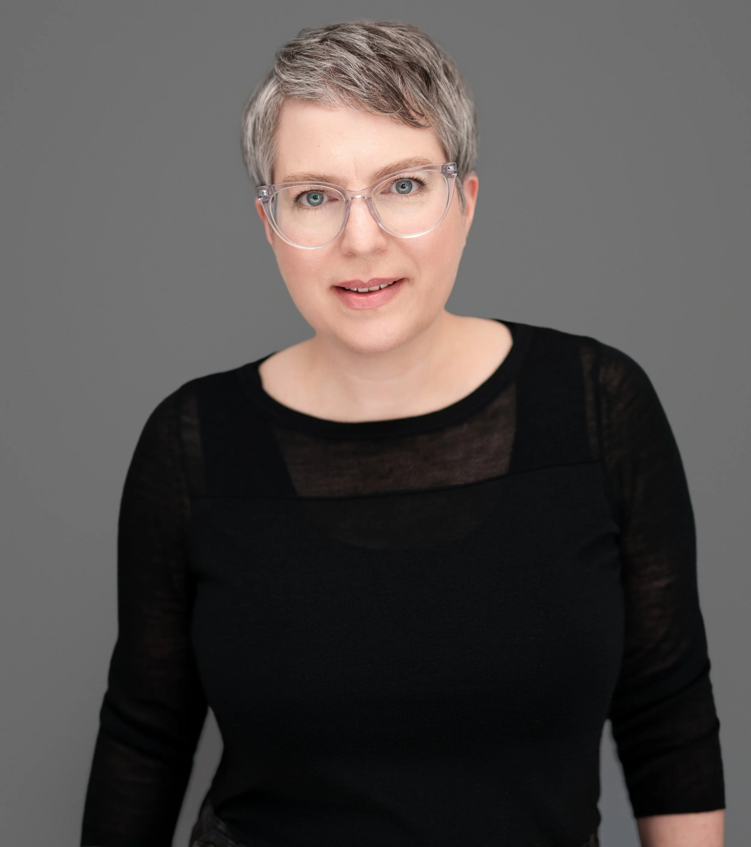 Portrait of a woman with a short gray pixie haircut and glasses.