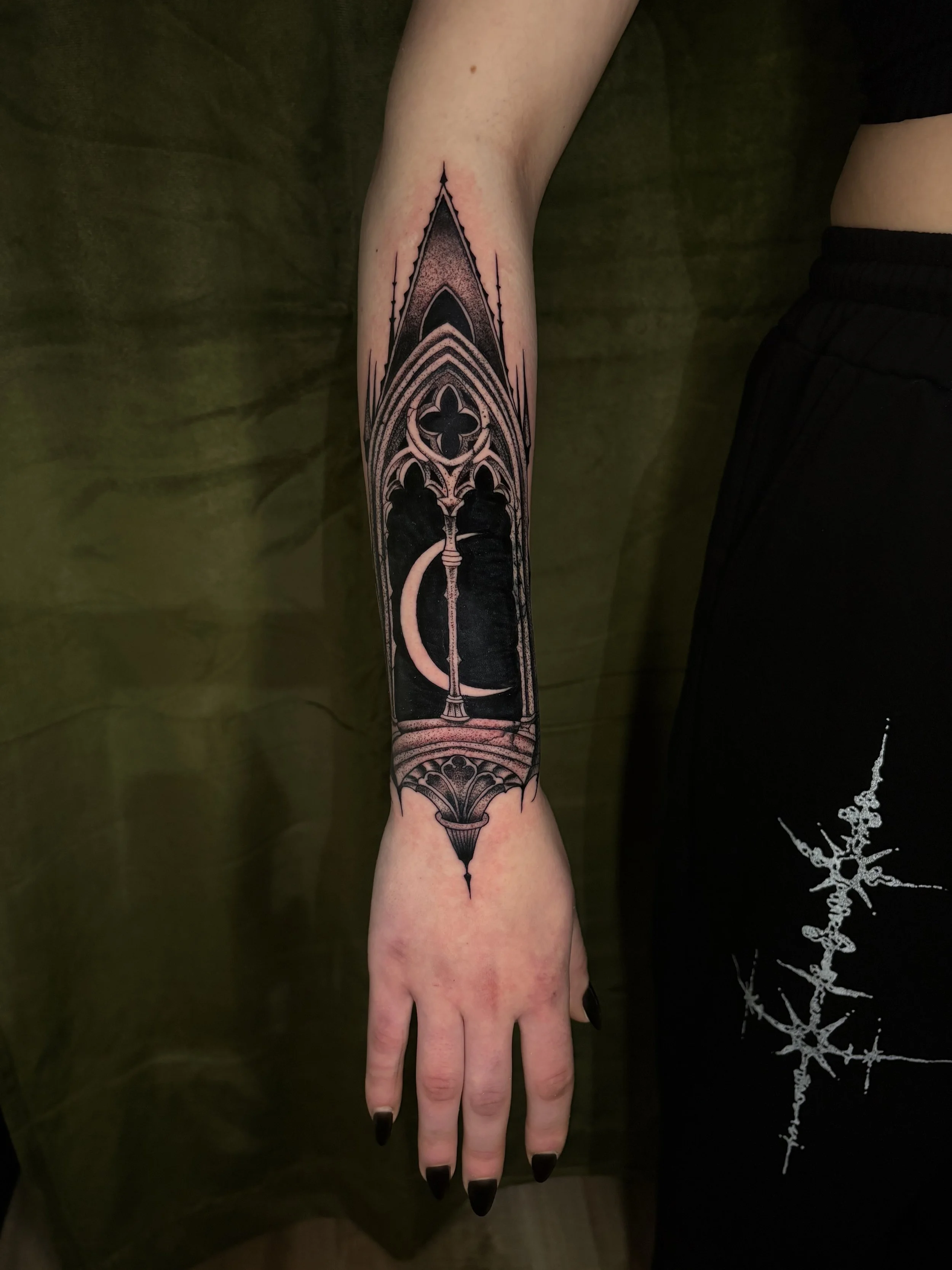 Close-up of a person's arm with a large black and gray geometric tattoo extending from their wrist to their elbow.