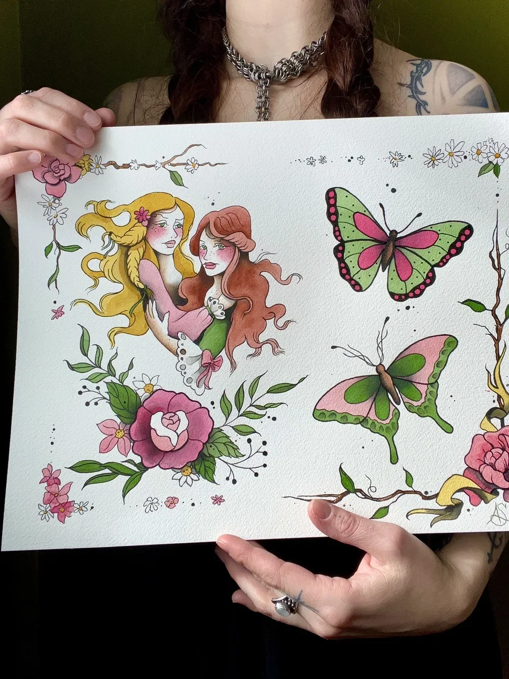 A person holding a colorful illustration featuring two women surrounded by flowers and two butterflies.