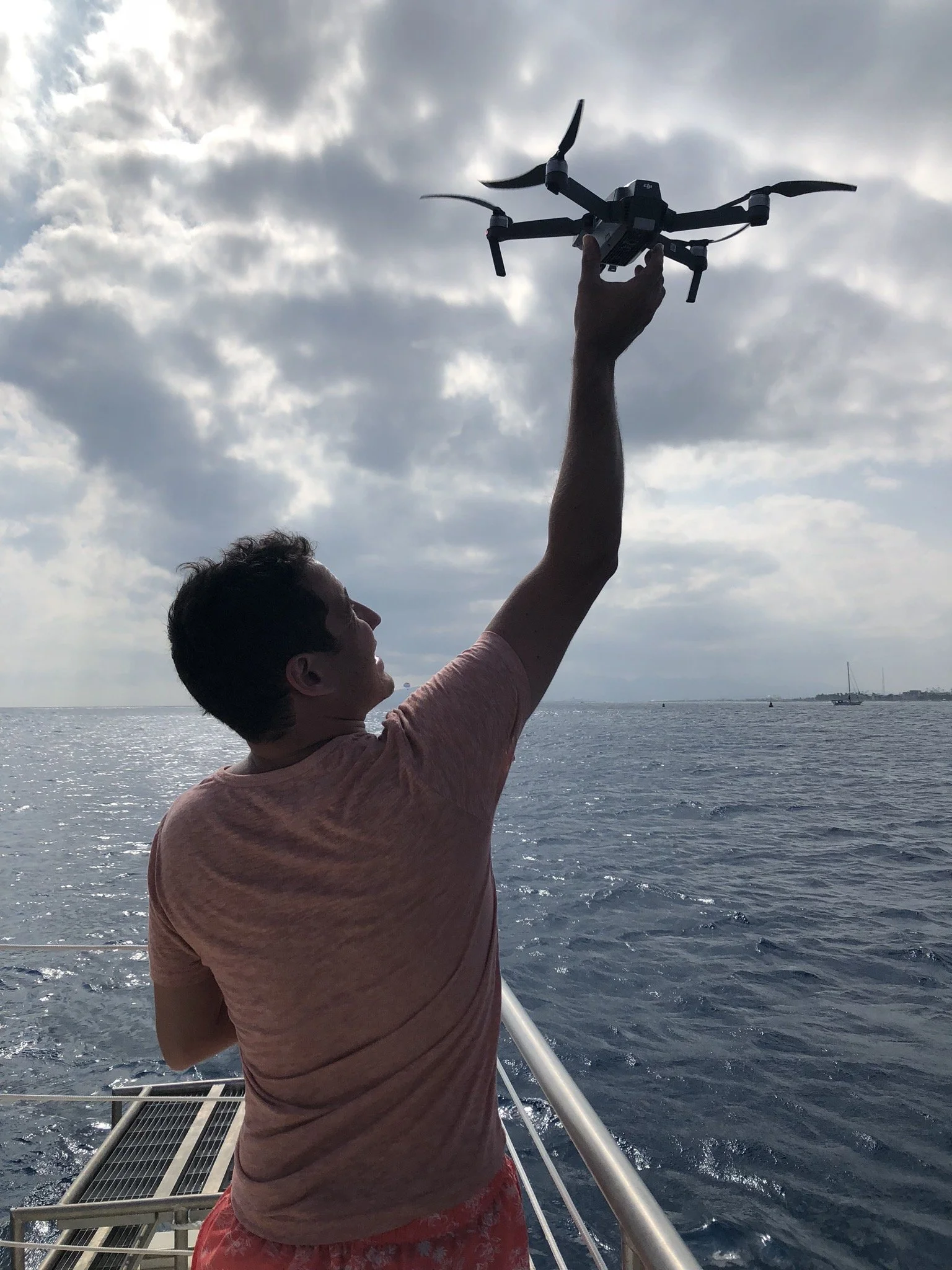Arnaud Muller holding a drone above the water beneath a cloudy sky