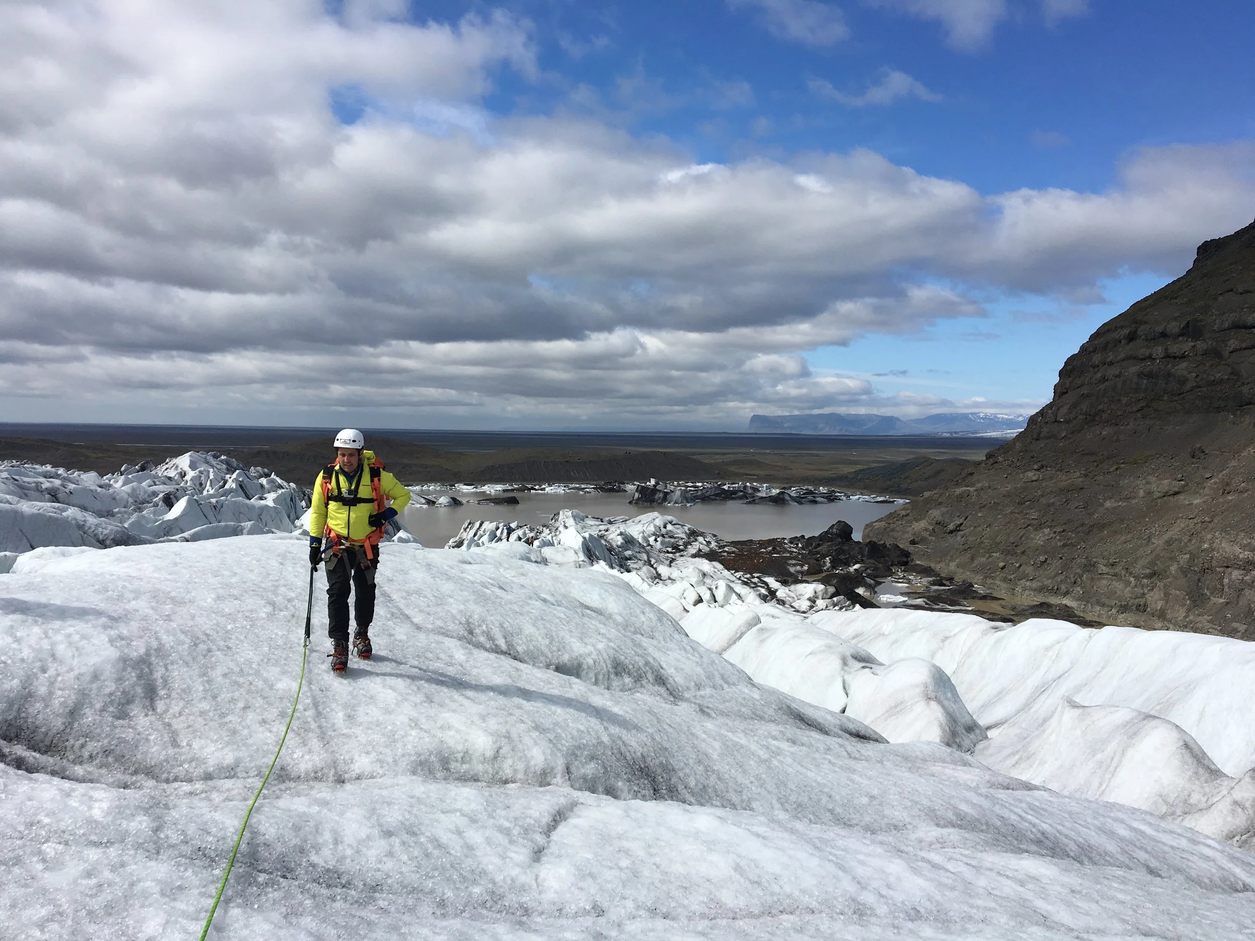 A traveler standing on ice beneath a cloudy mountain sky