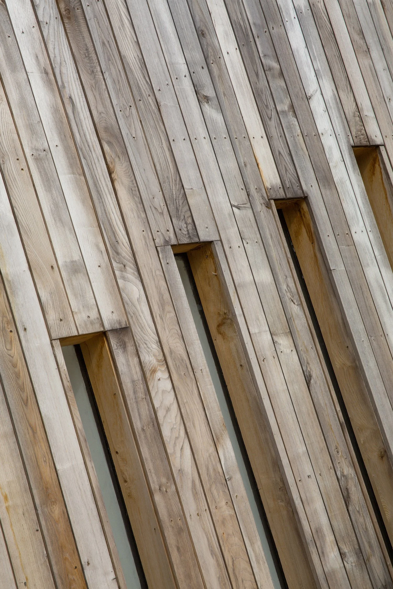 Close-up of a wooden wall with vertical planks and small square windows.