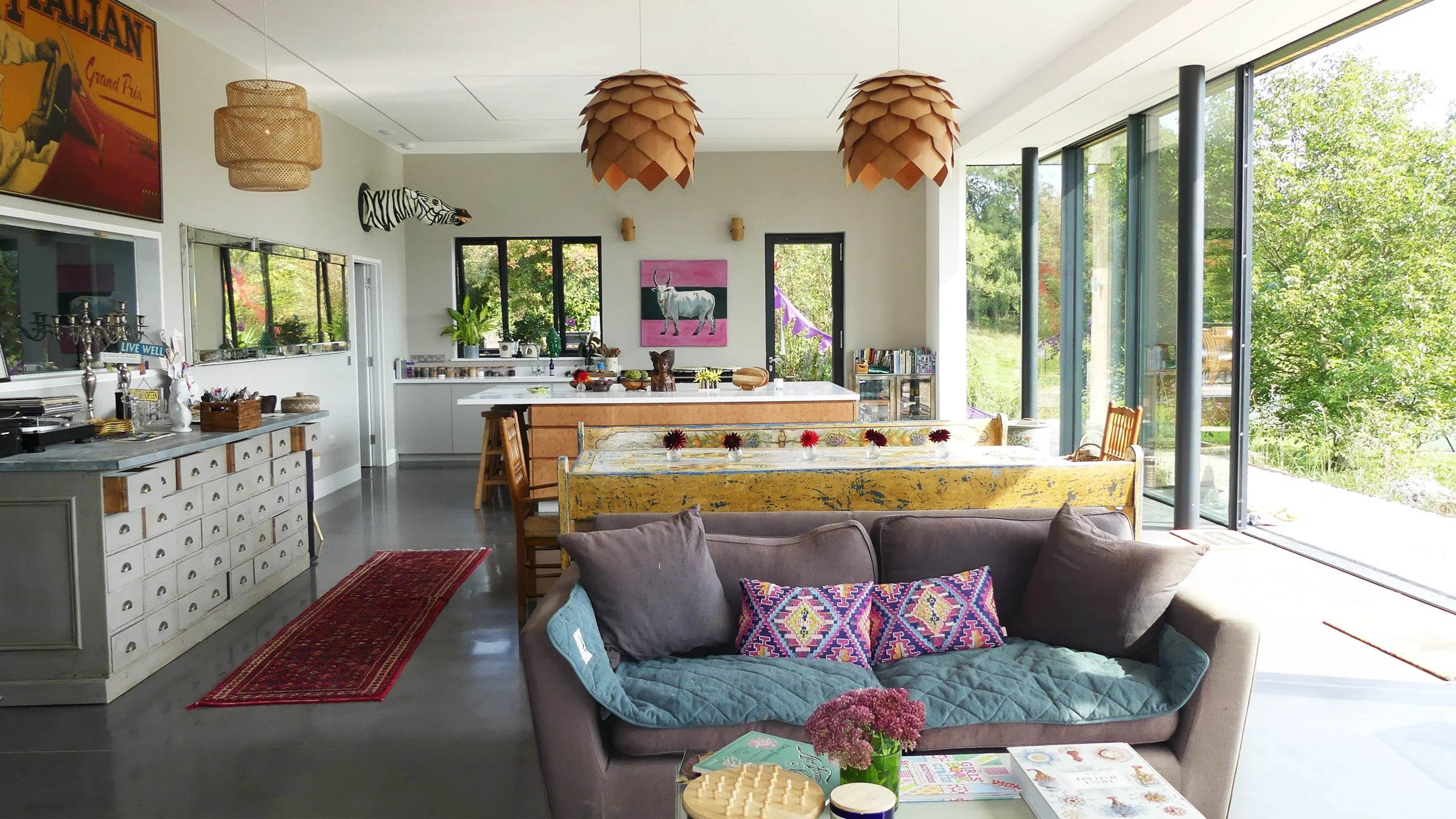 Modern open-concept living room and kitchen with large windows, eclectic decor, and colorful accents.