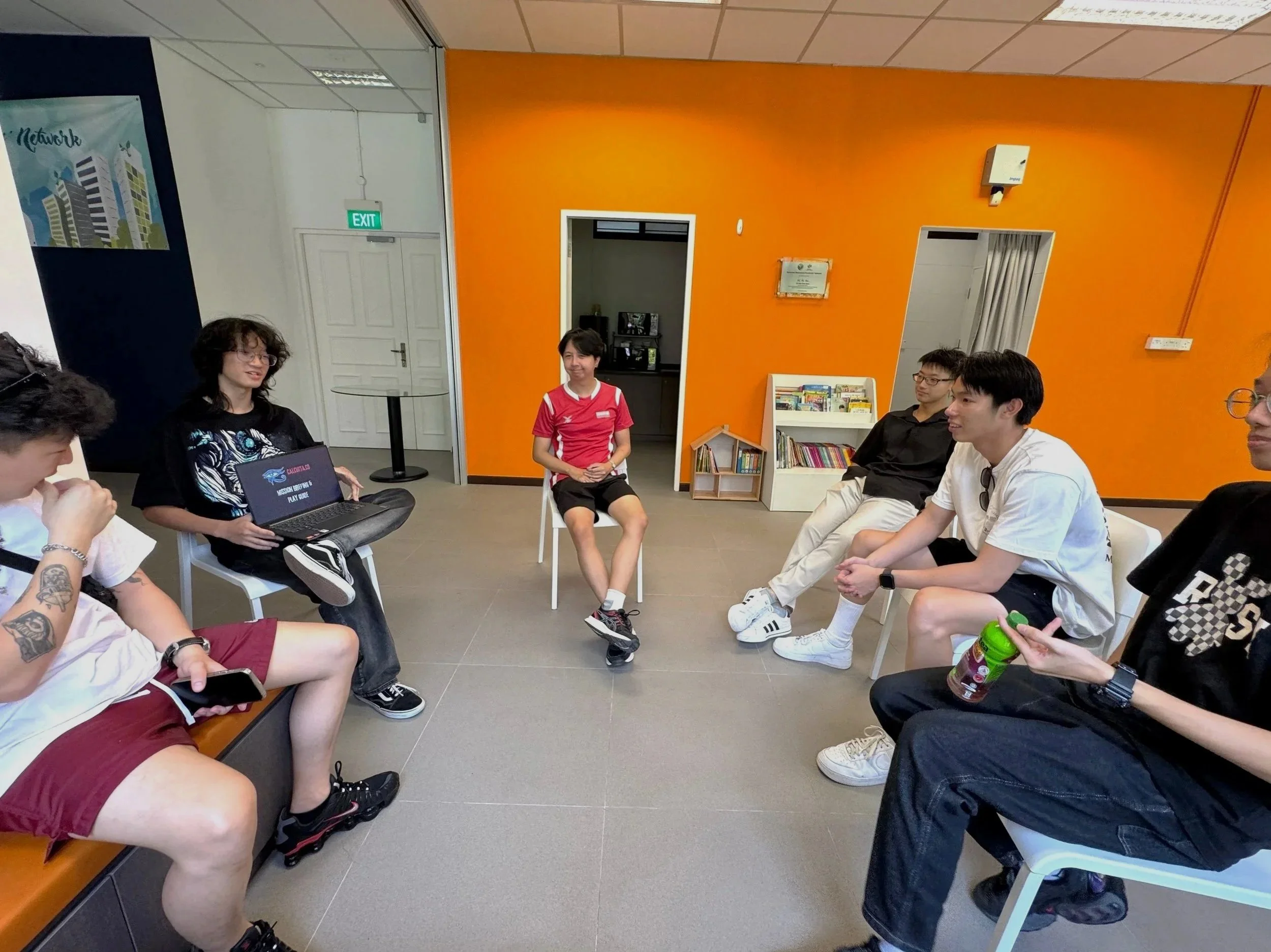 A group of players being briefed by a gamemaster for their upcoming amazing race.