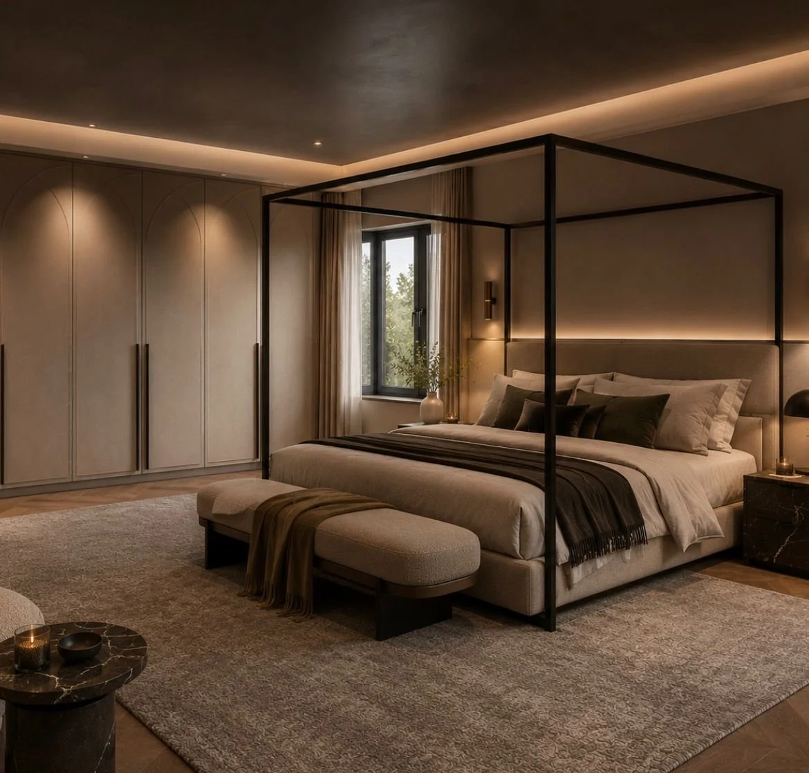 A modern bedroom with a four-poster bed, beige and gray bedding, black accents, a large closet with arched doors, a window with curtains, a bench at the foot of the bed, and a rug on the wooden floor.