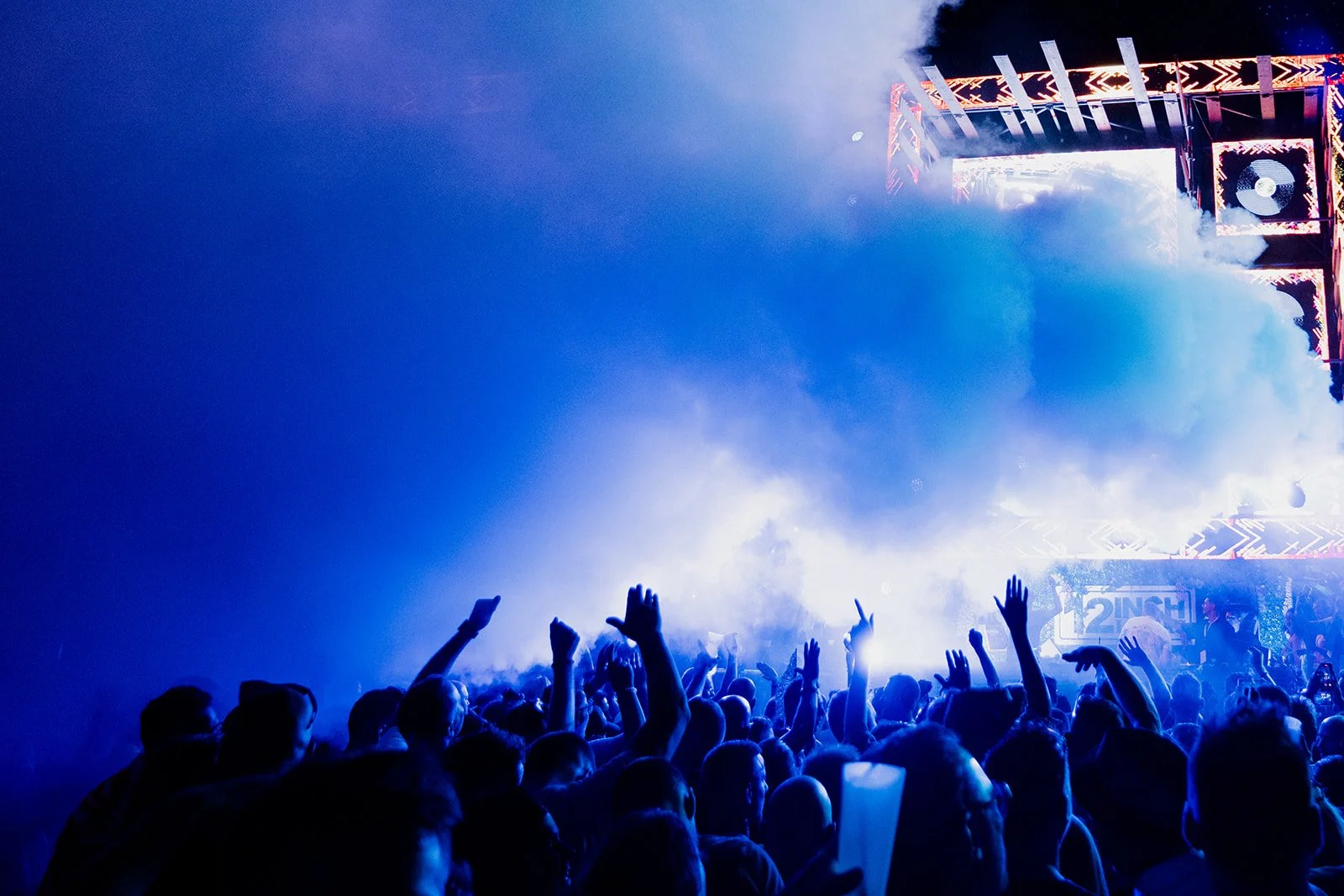 B2 Photography Jakob Hallaert  - Een concert met een grote menigte mensen die naar het podium kijken, omringd door blauwe en witte lichten, met een podium en schermen op de achtergrond.