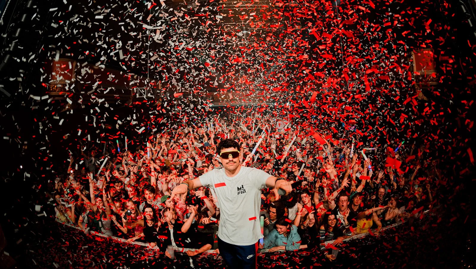 B2 Photography Jakob Hallaert  - Man in het midden met zonnebril voor een menigte op een feest met confetti en rode en witte papierschuivers