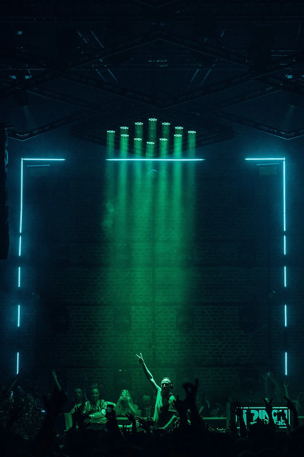 B2 Photography Jakob Hallaert  - Een DJ die optreedt in een club met groene en blauwe lichten, omringd door een publiek dat danst.