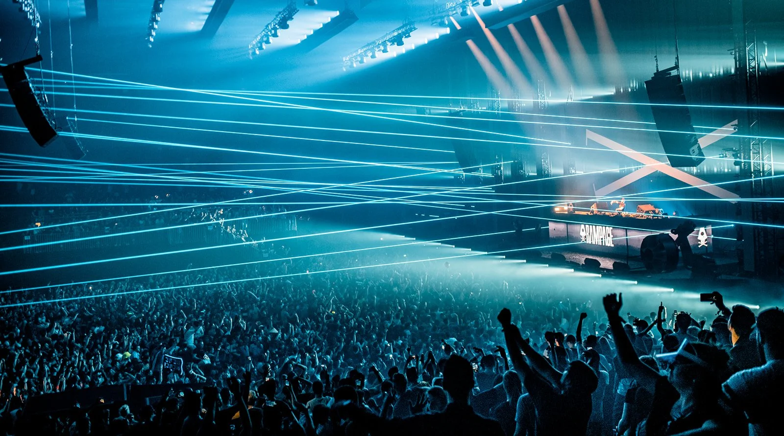 B2 Photography Jakob Hallaert  - Een druk muziekfestival met een groot publiek en een DJ-standaard, verlicht door blauwe laserlichten.