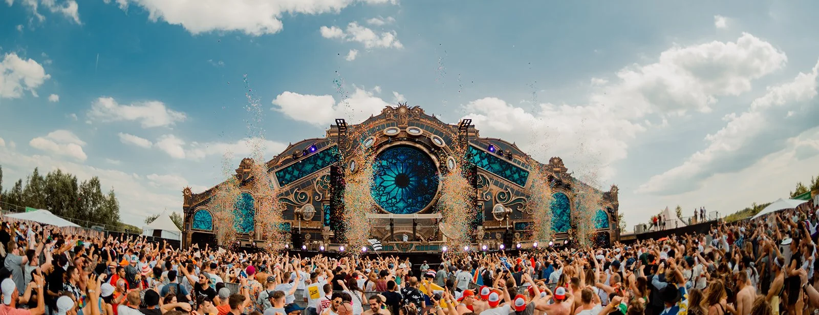 B2 Photography Jakob Hallaert  - Grote muziekfestivaltent met publiek en confetti in de lucht, heldere blauwe lucht met wolken.