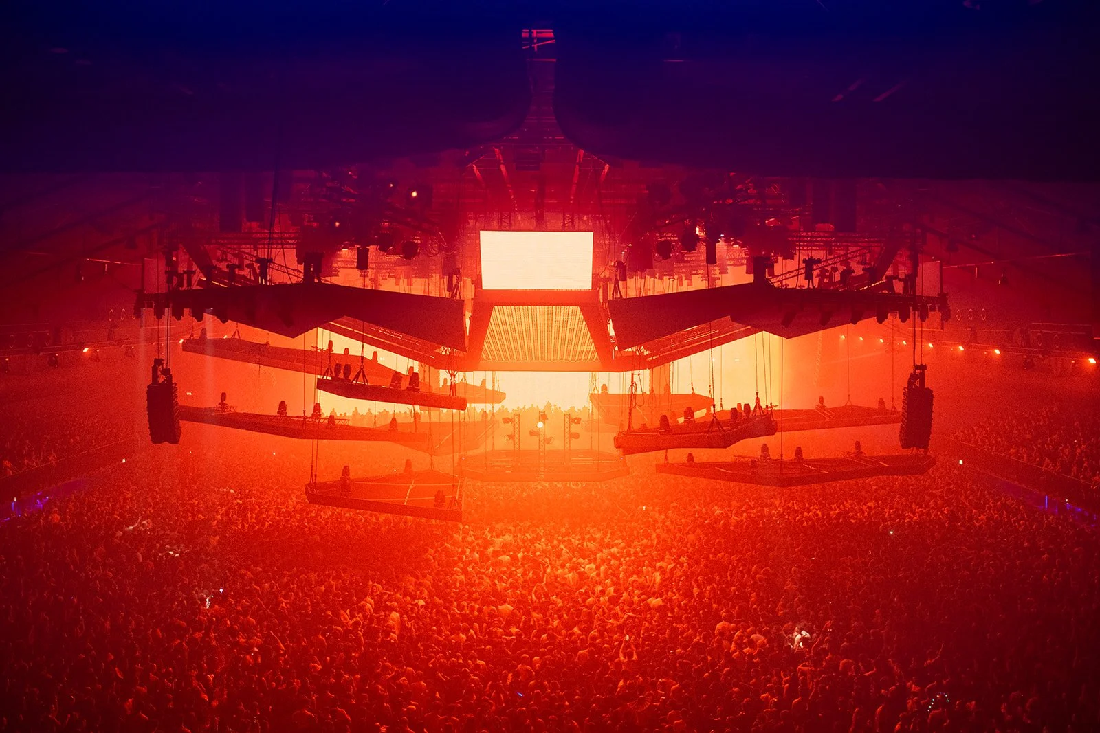 B2 Photography Jakob Hallaert  - Grote menigte in een donker verlichte concertzaal met rode verlichting en grote schermen.