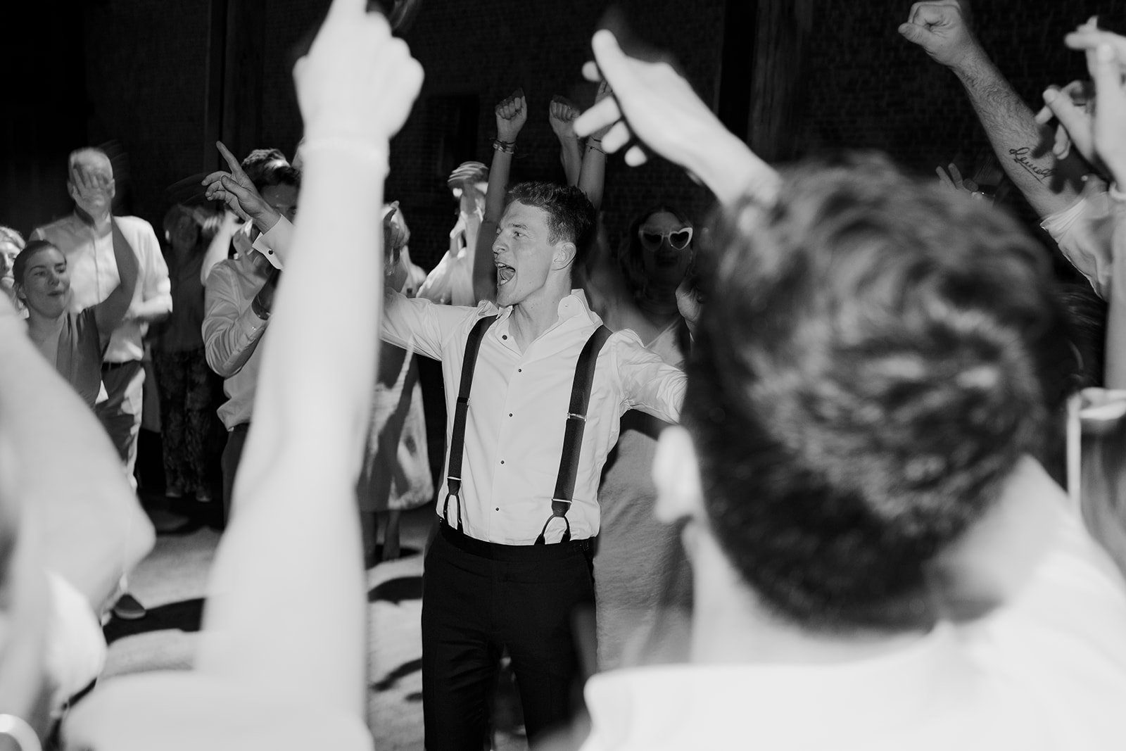 B2 Photography Jakob Hallaert  - Mannen danst en zingt in een groep mensen op een feestje, iedereen heeft zijn handen in de lucht en er hangt een feestelijke sfeer.