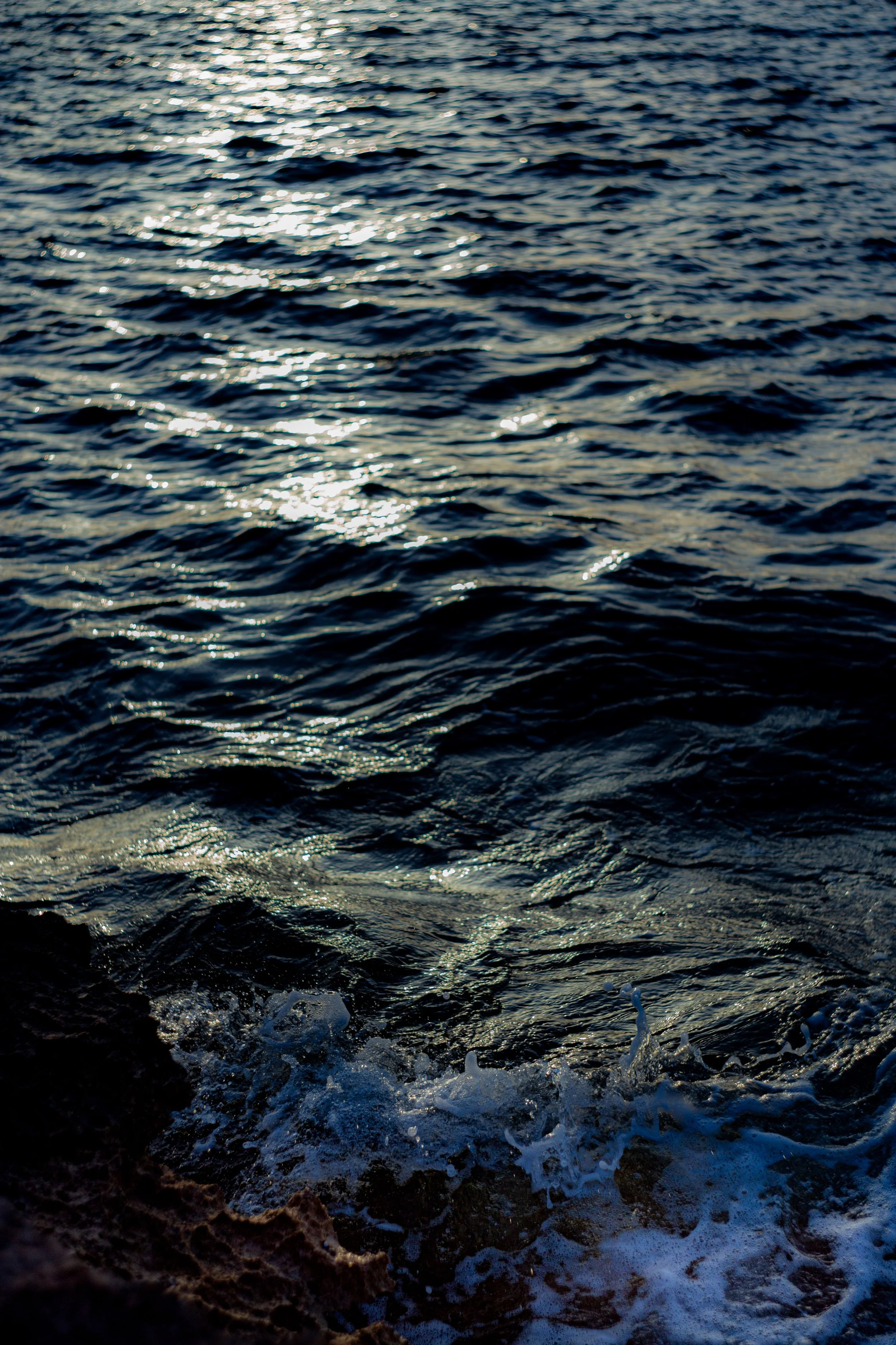 Sea on the shore with dark waters and reflections of the sun.