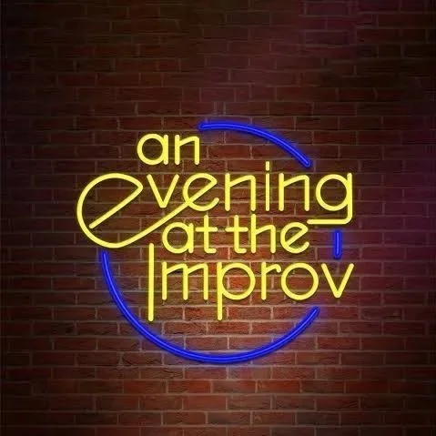 Neon sign on a brick wall reading 'an evening at the improv' with yellow and blue lights.