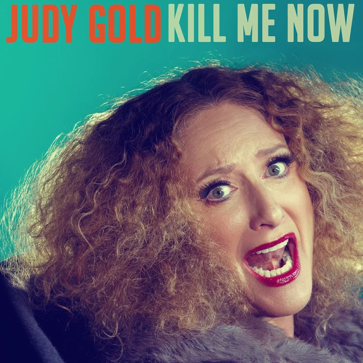 Album cover featuring a woman with curly red hair, wearing makeup and a fur coat, shouting or singing with an intense expression. Text on top reads "Judy Gold Kill Me Now".