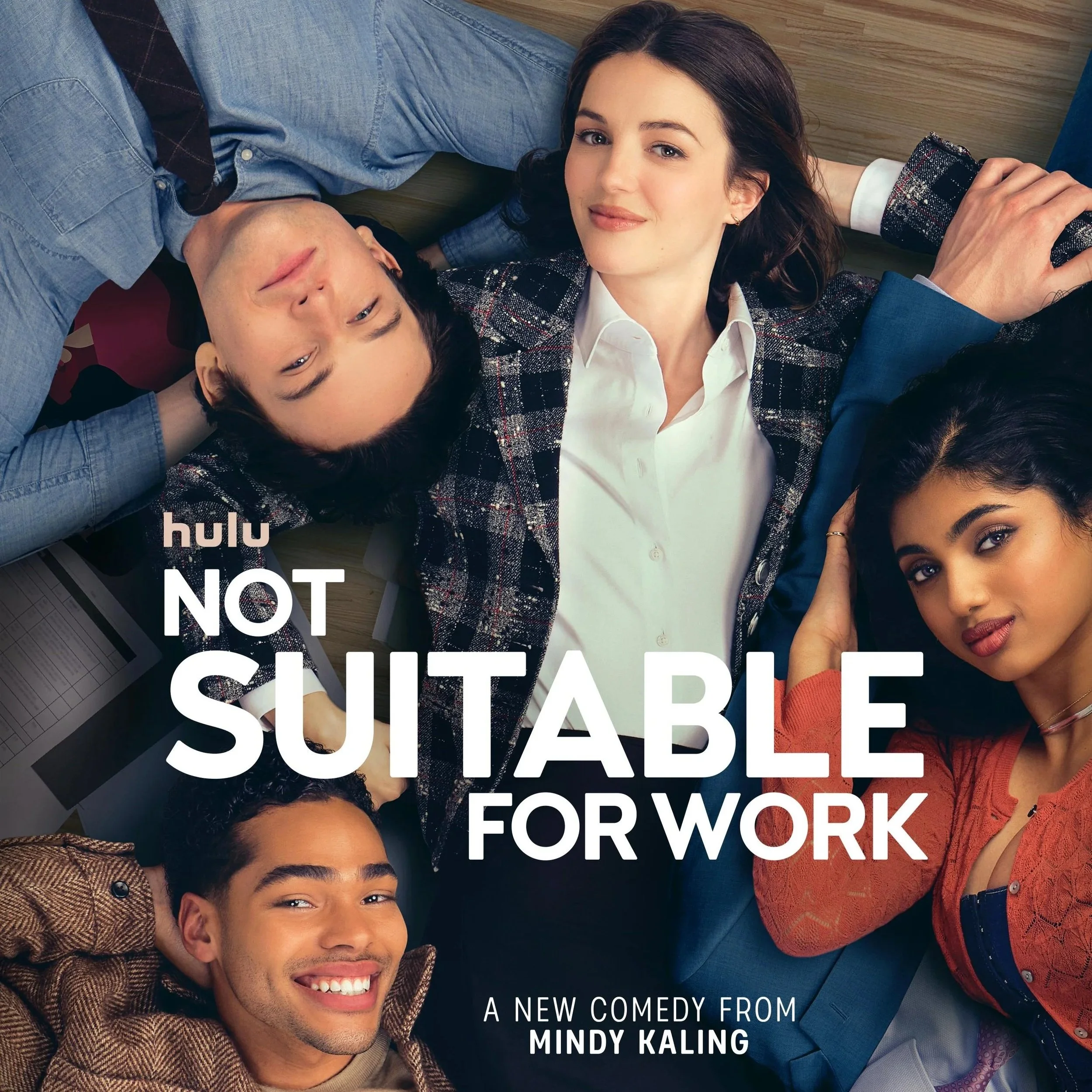 Group of diverse young adults lying on the floor, smiling and looking at the camera, with bold white text overlaying the image promoting a comedy from Mindy Kaling on Hulu.