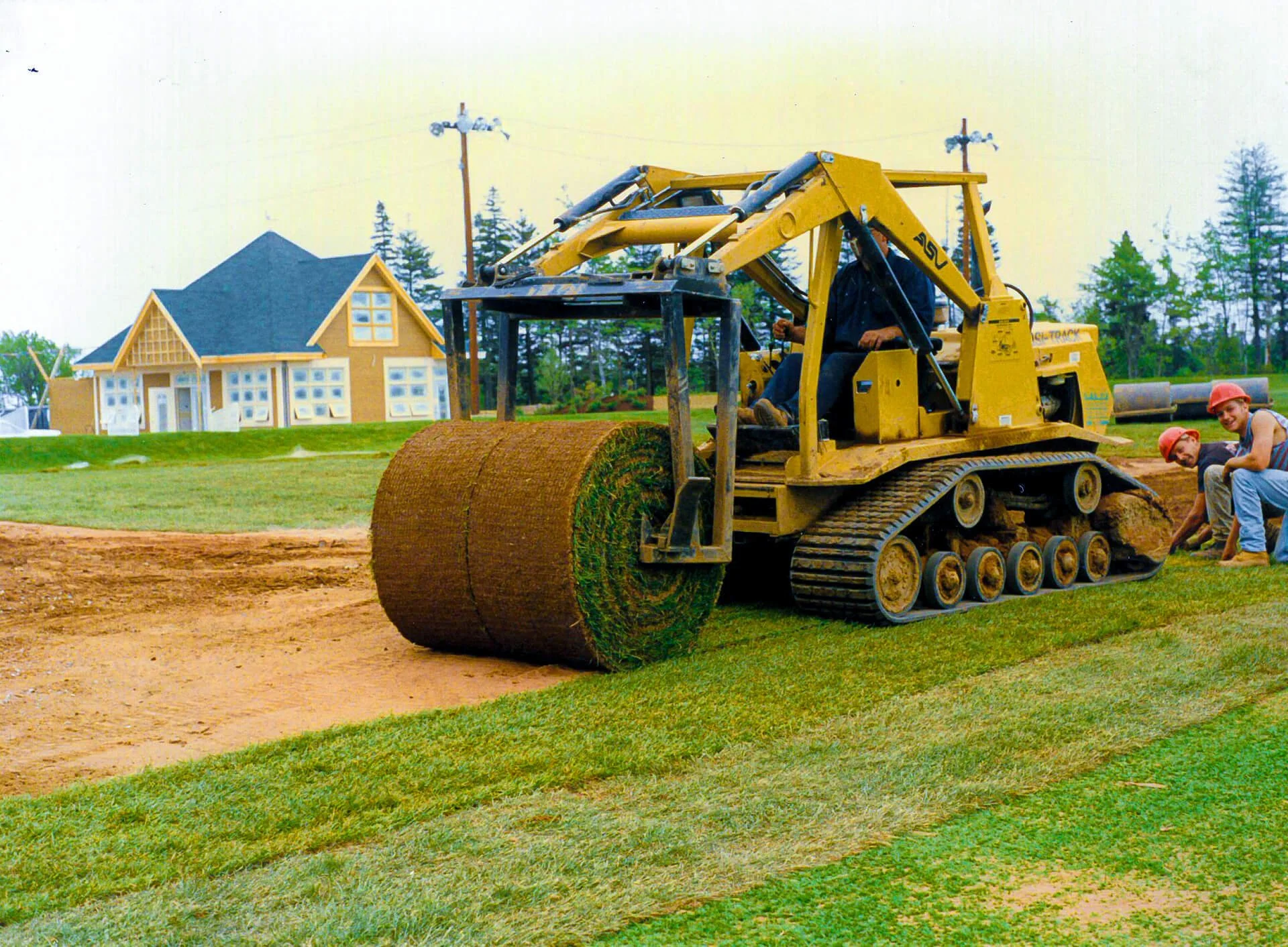 Large yellow sod laying machine rolling out grass