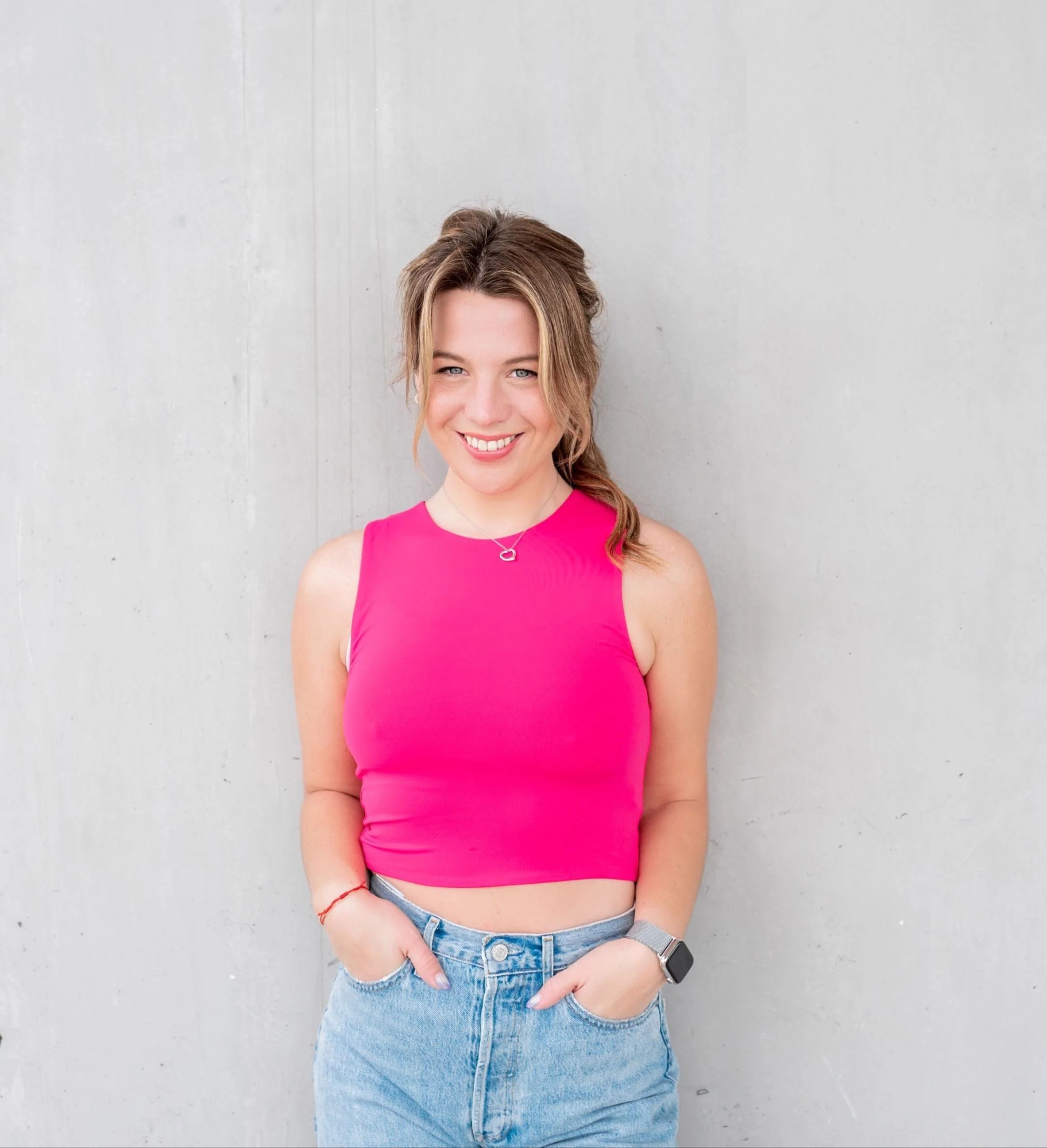 Woman wearing a pink shirt in front of a gray wall