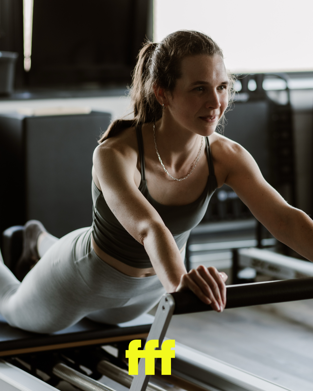 Vrouw die op een reformer Pilates machine oefent in een sportschool.