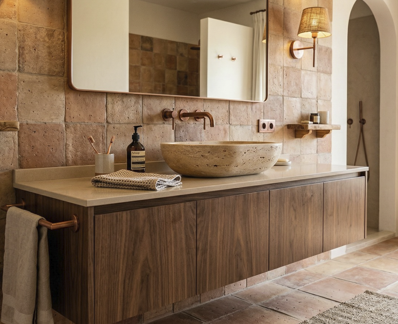 Lavabo de piedra y mueble de madera en baño con paredes de ladrillo y lámpara de pared