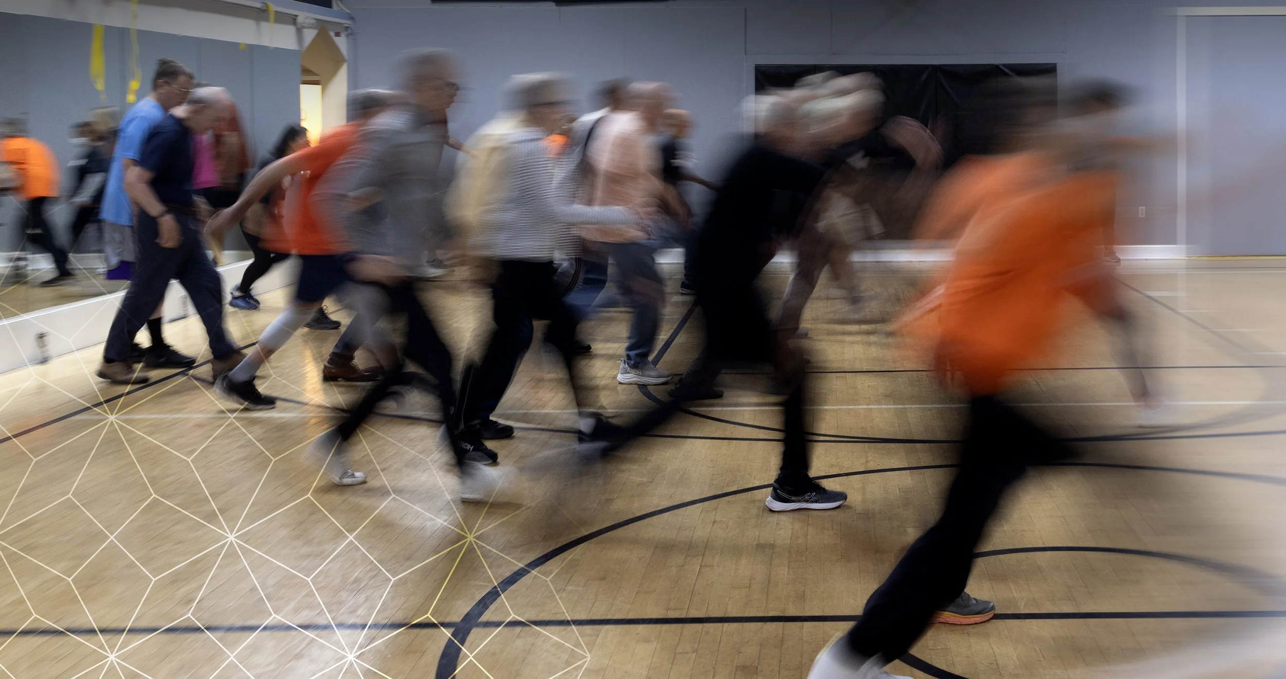 A group of people are walking in a line inside a gymnasium.