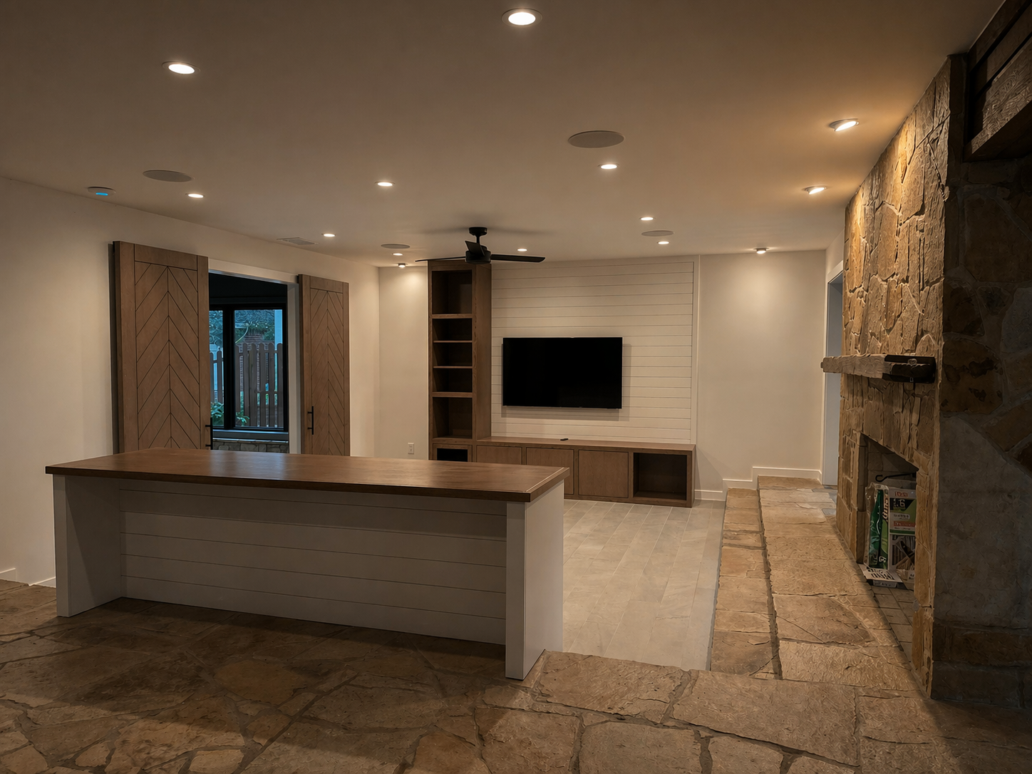 Renovated living room at Lake McQueeney Residence with original sandstone columns, two-sided stone fireplace, and dropped living area.