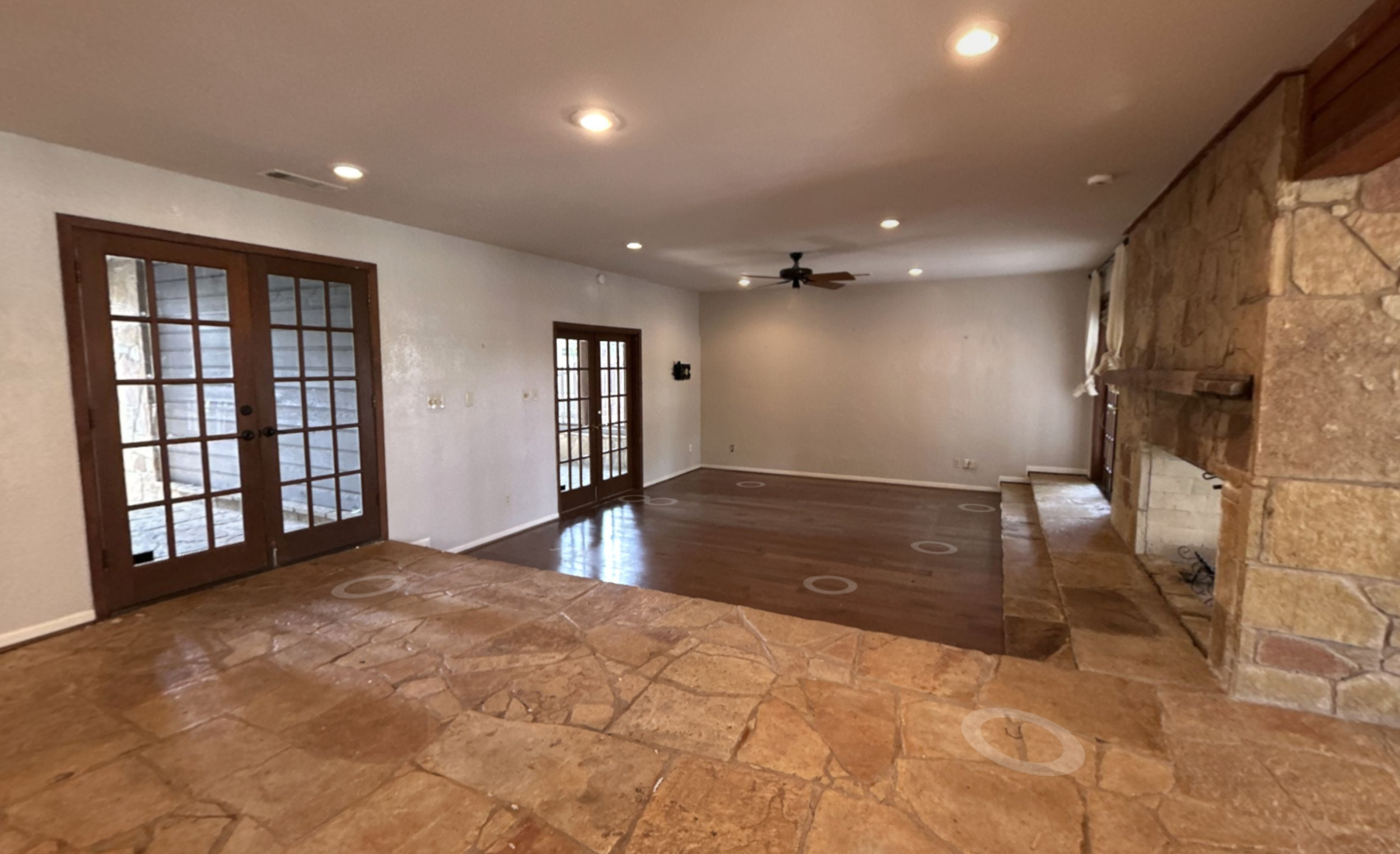 Before photo of the Lake McQueeney Residence living room showing the original dropped living area, sandstone columns, and two-sided stone fireplace prior to renovation.