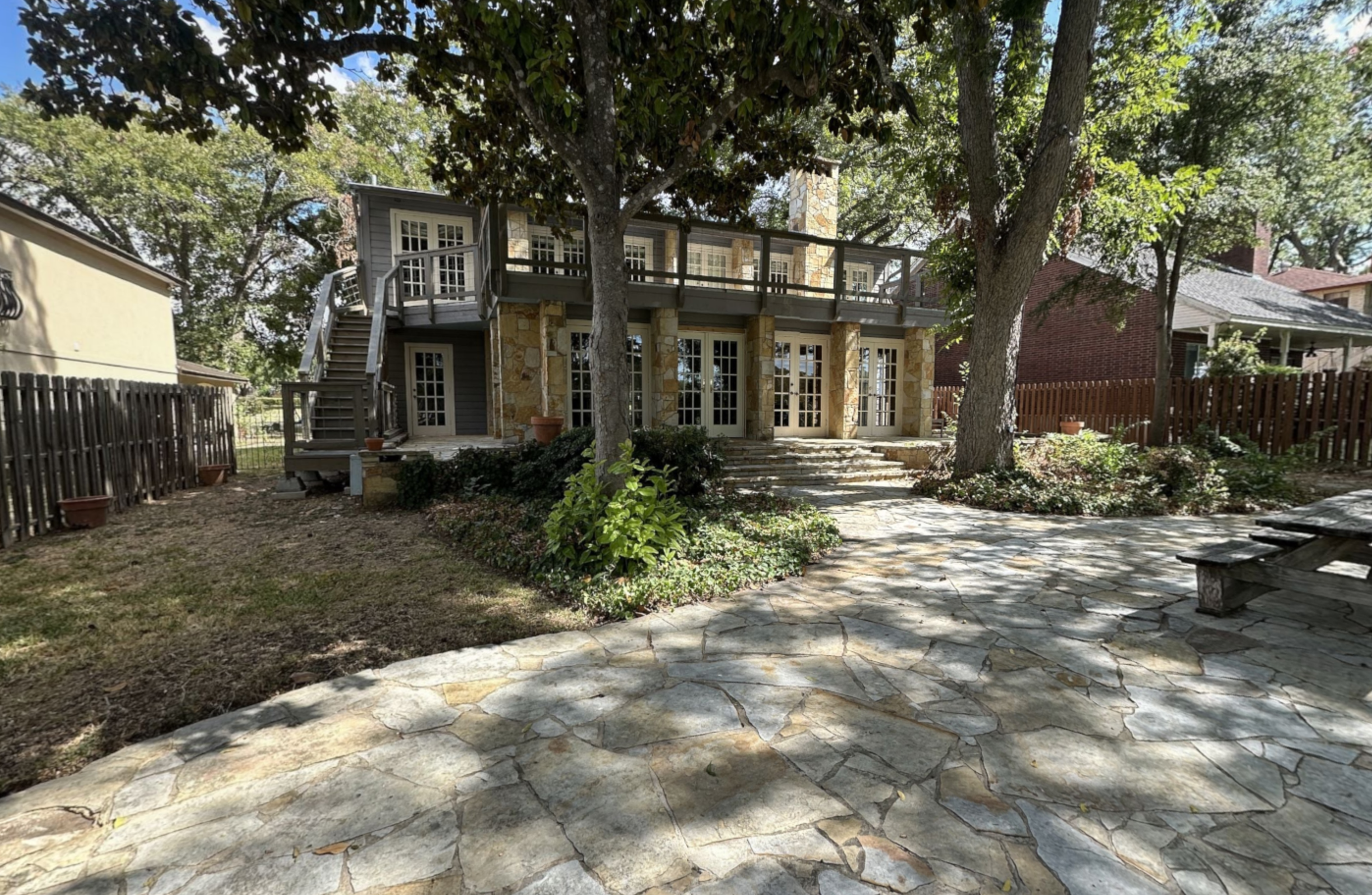 Before photo of the lake-facing exterior at the Lake McQueeney Residence showing the original rear elevation and outdoor living areas prior to renovation.