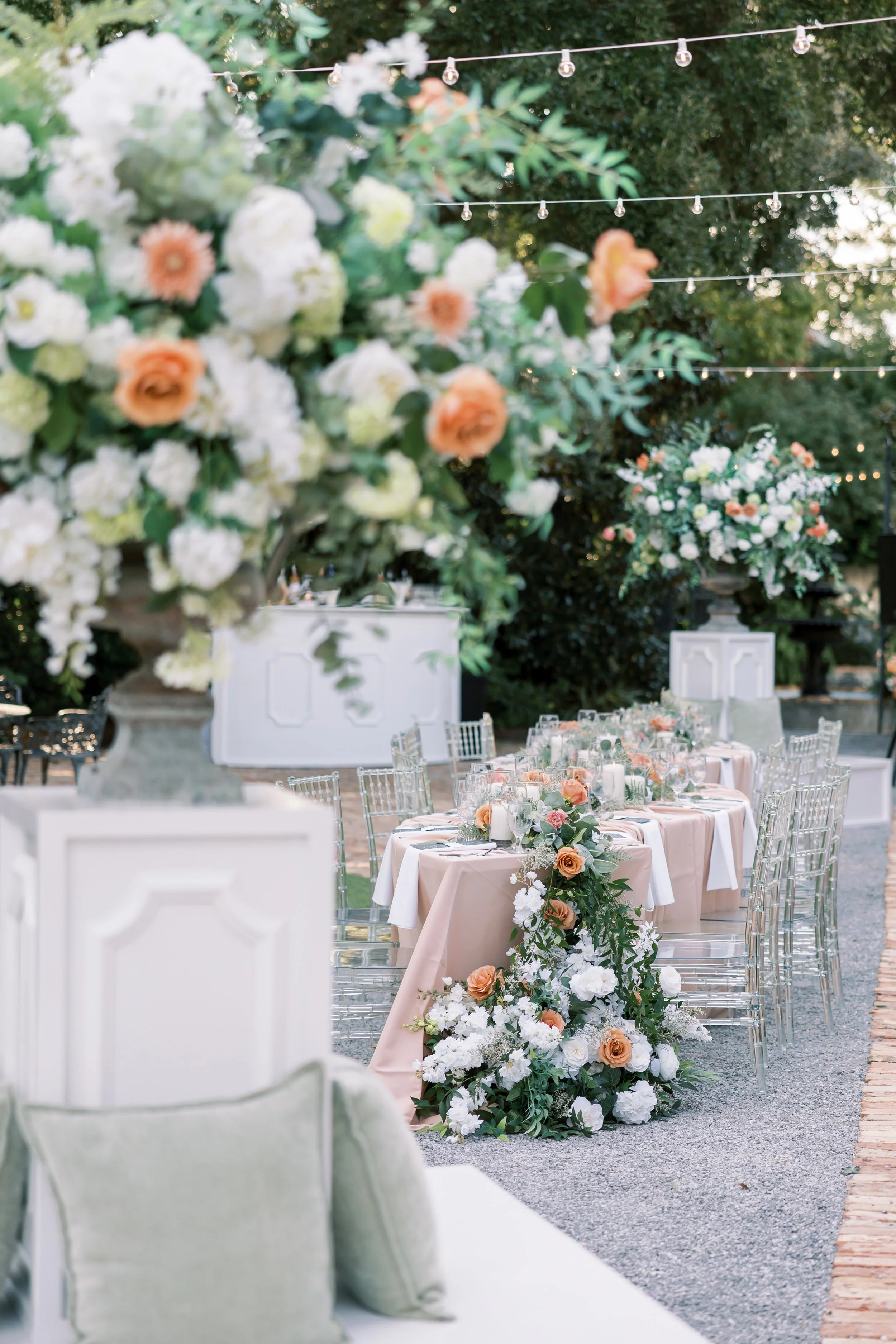 Elegant outdoor wedding reception setup with long table, floral arrangements, and string lights at a Pensacola Wedding Venue.