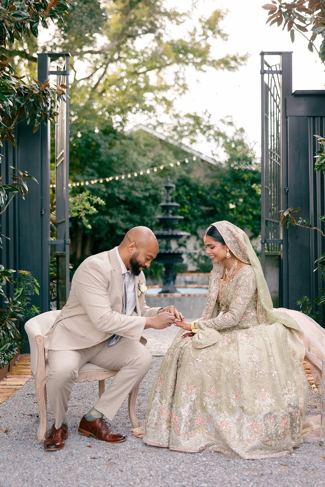 A bride and groom share a moment during their wedding ceremony outdoors, with trees and string lights in the background.