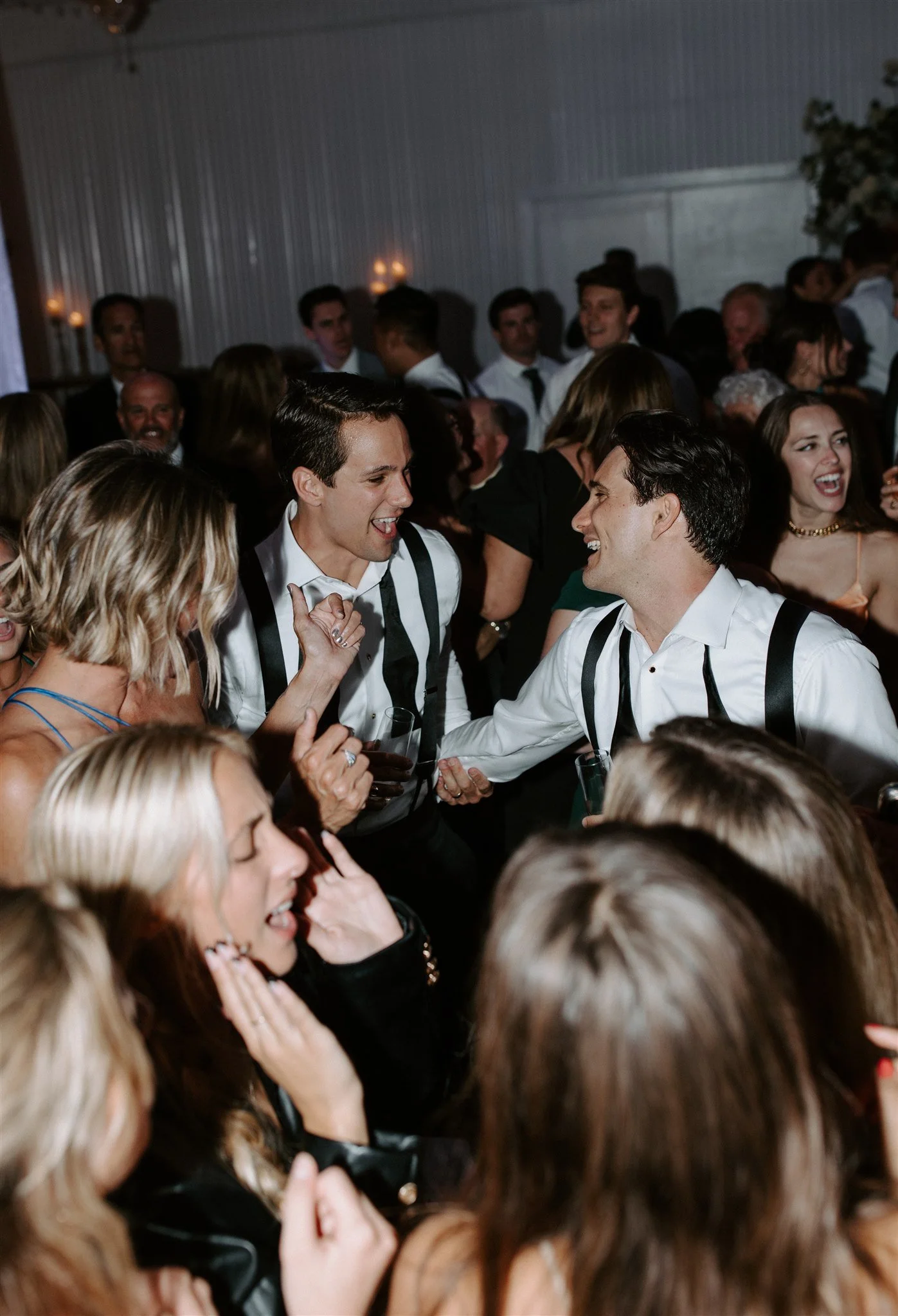 People dancing and socializing at a lively party or celebration, with men and women smiling and enjoying themselves.