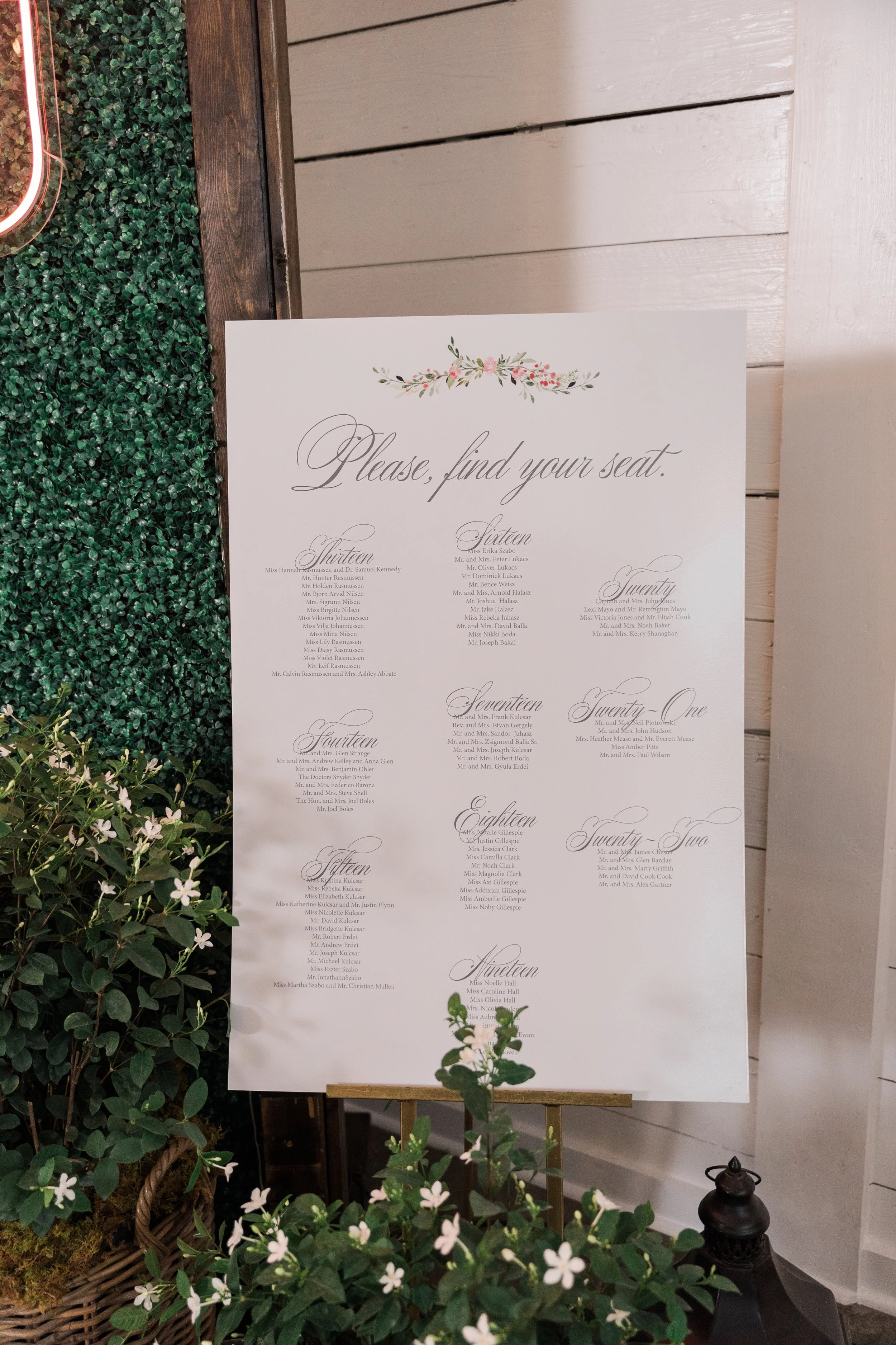 Wedding seating chart with floral decorations and greenery.