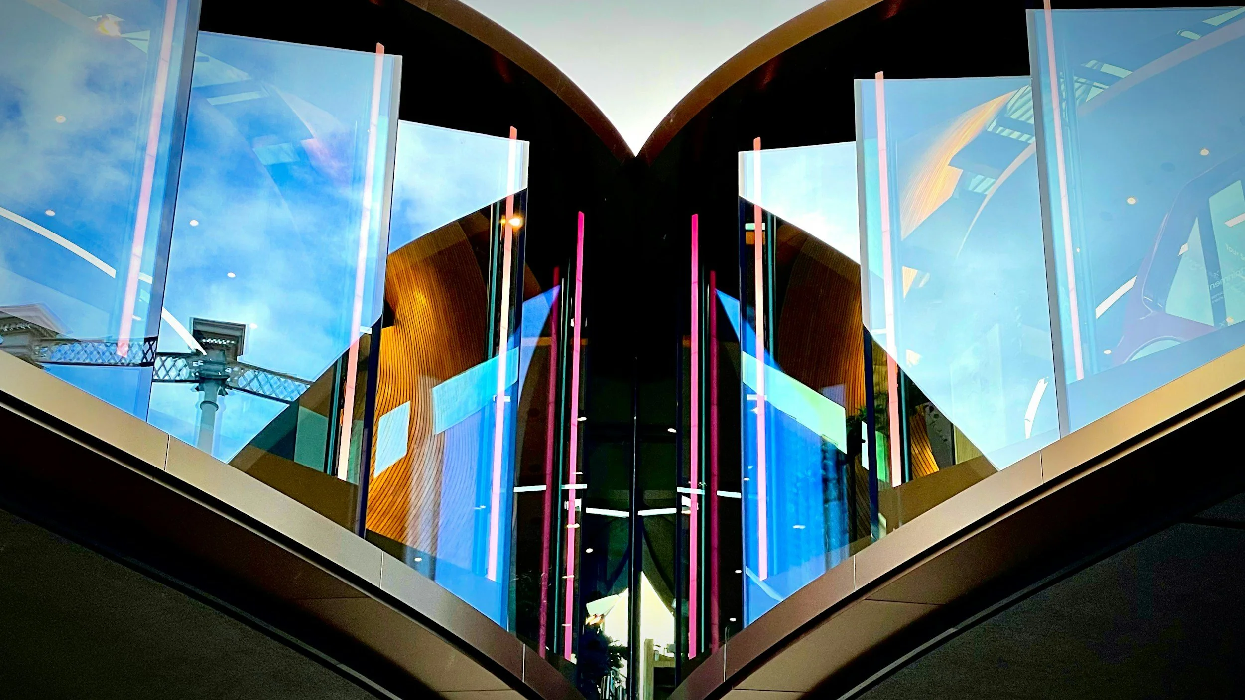Centaral Victorian House | Coal Drops House | Samsung | A modern building with large glass windows and colorful vertical lights, viewed from below during sunset.