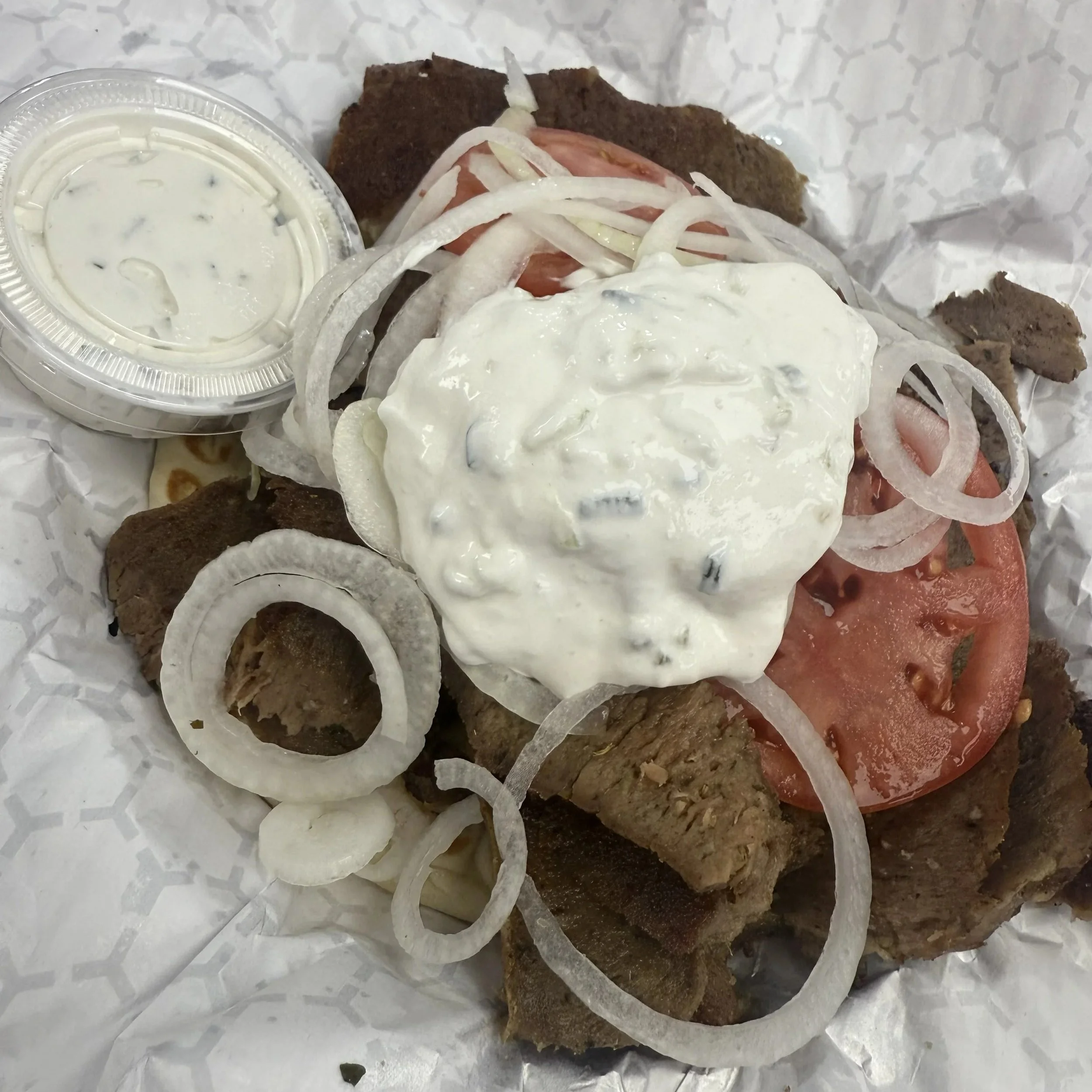 AJ’s Restaurant & Deli Kenosha gyro with seasoned meat, fresh toppings, pita, and creamy sauce.