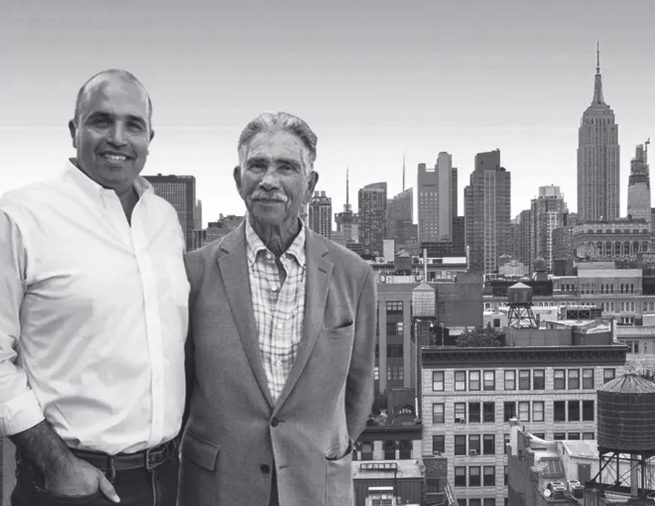 Two men standing on a rooftop with New York City skyline, including the Empire State Building, in the background.