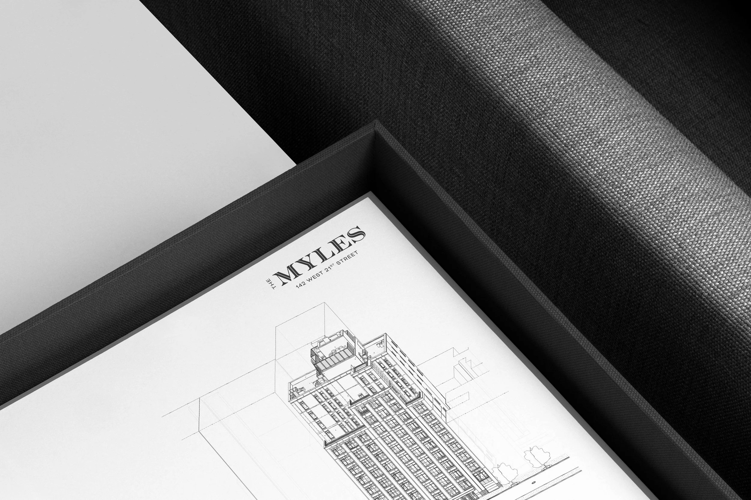 Close-up of a black box containing architectural blueprints and a sheet titled "The Moxies" for a building on West 21st Street.