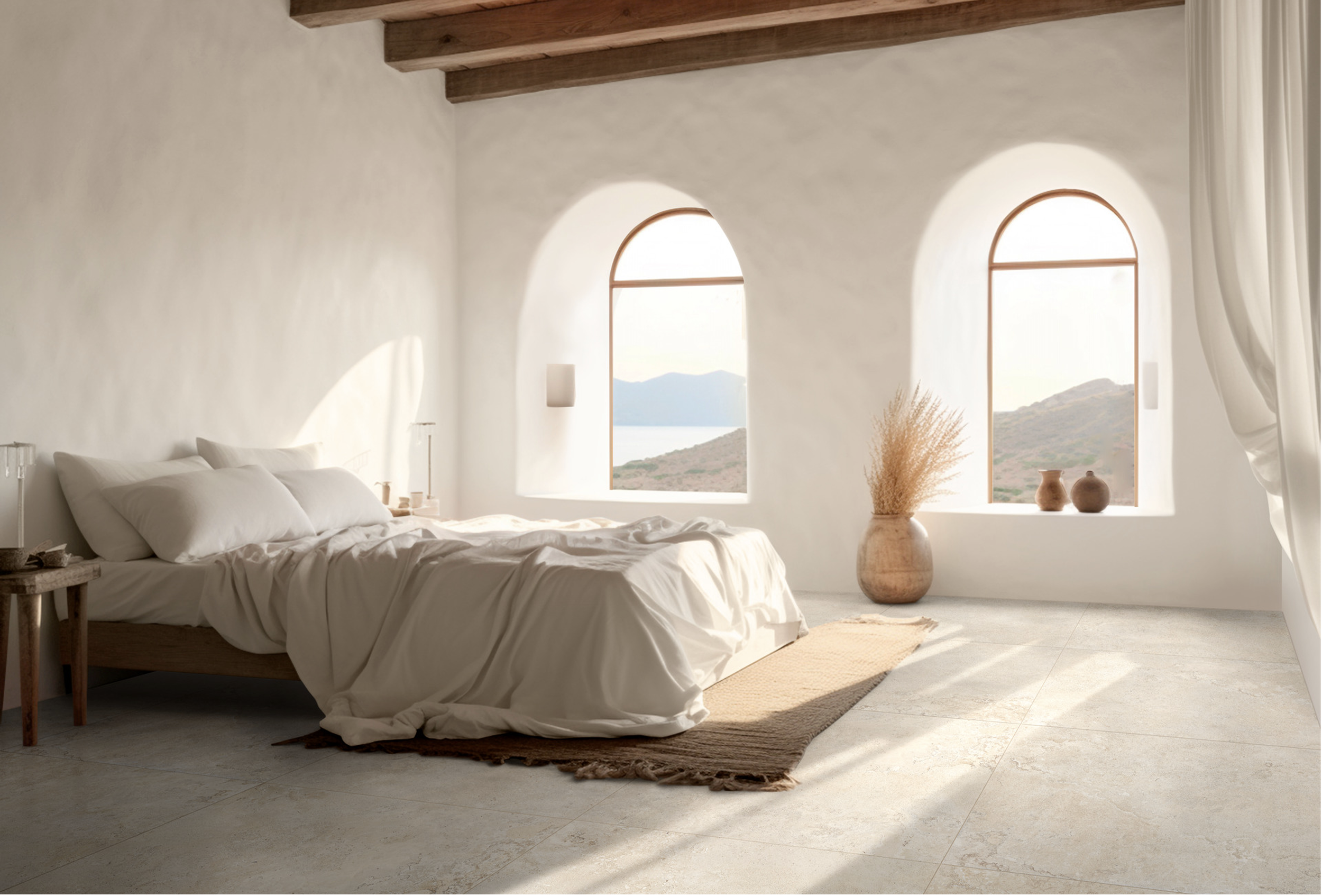 A bright, minimalistic bedroom with a white bed, wooden beams on the ceiling, arched windows showing a mountain and lake view, beige carpet, and decorative pottery near the window.