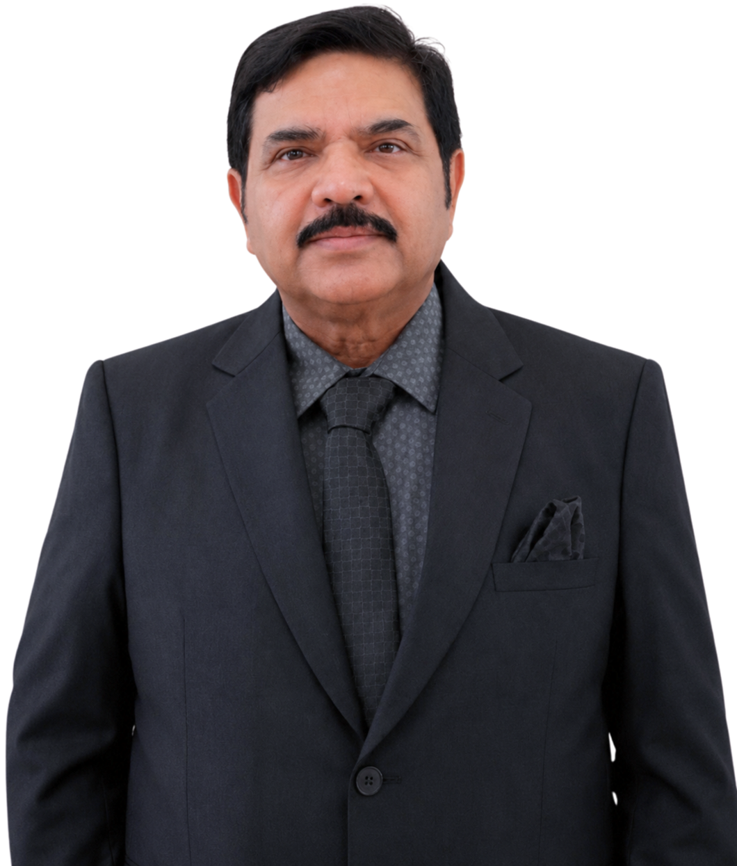 A middle-aged man with dark hair, a mustache, wearing a black suit, patterned gray shirt, and dark tie posing against a plain background.